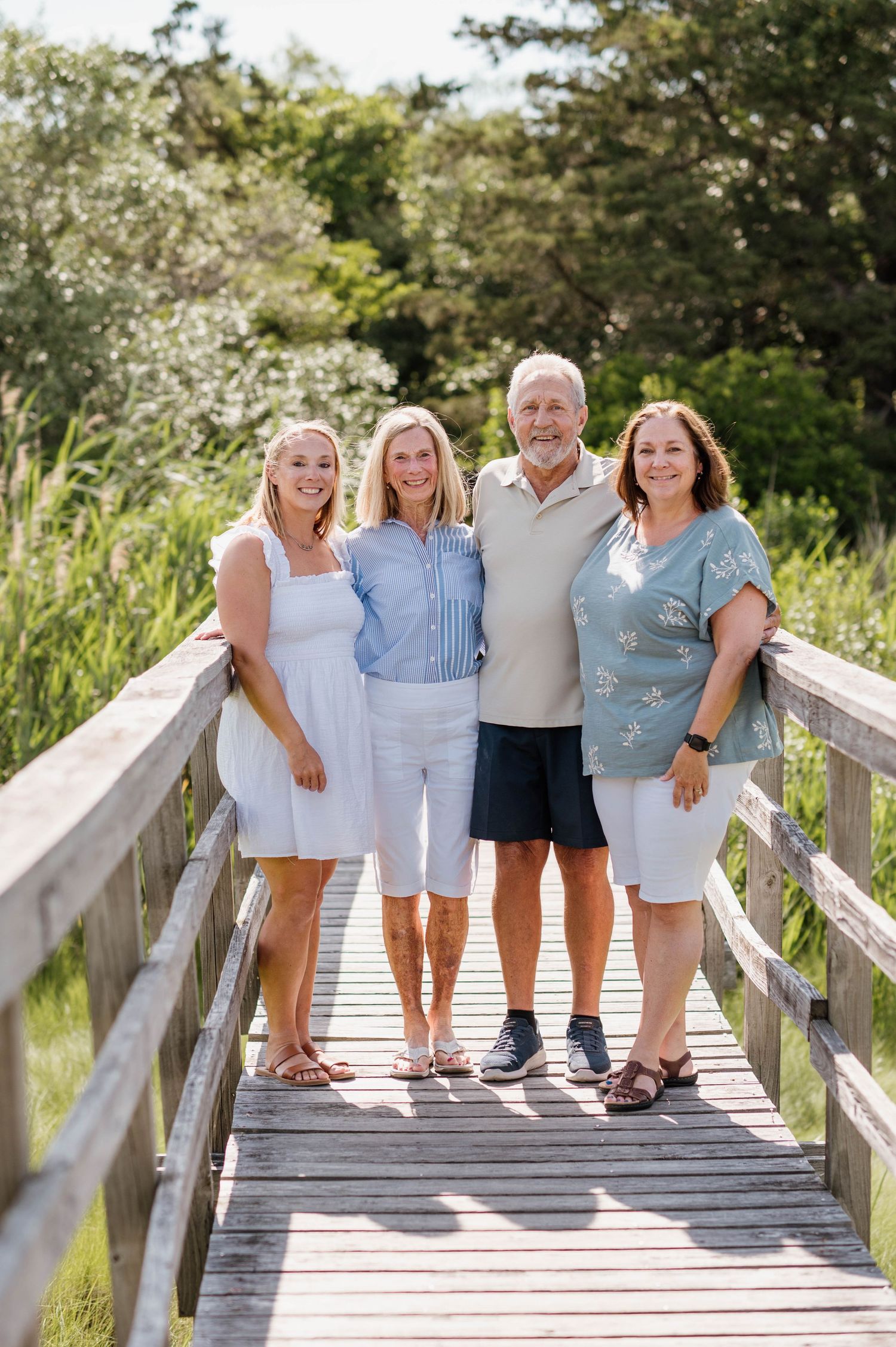 Group of people standing together on a wooden boardwalk in casual summer clothing.