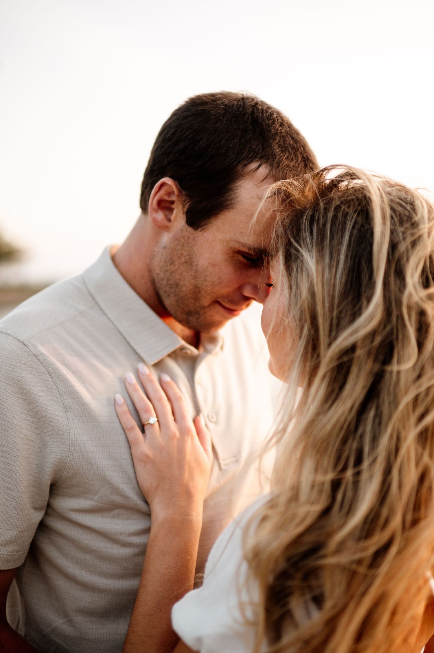 Intimate close-up of a couple sharing a tender moment in warm sunlight.
