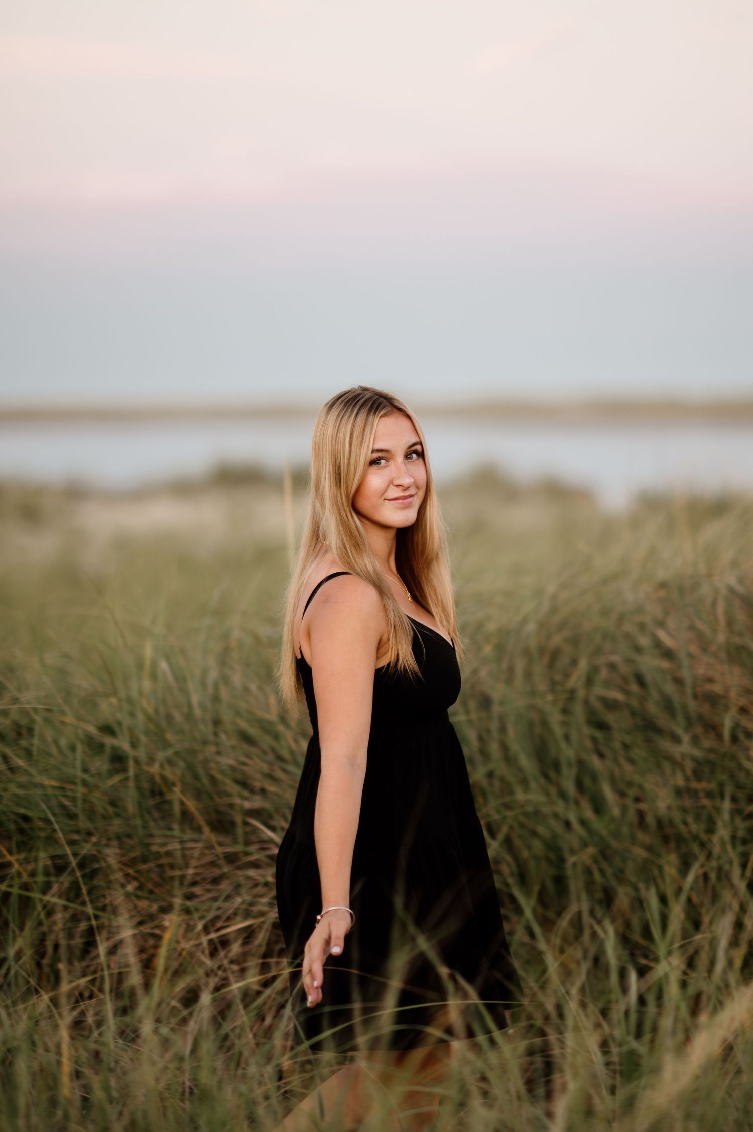 A sequence of sunset portraits in tall grass showing someone wearing a black tank top against a coastal backdrop.