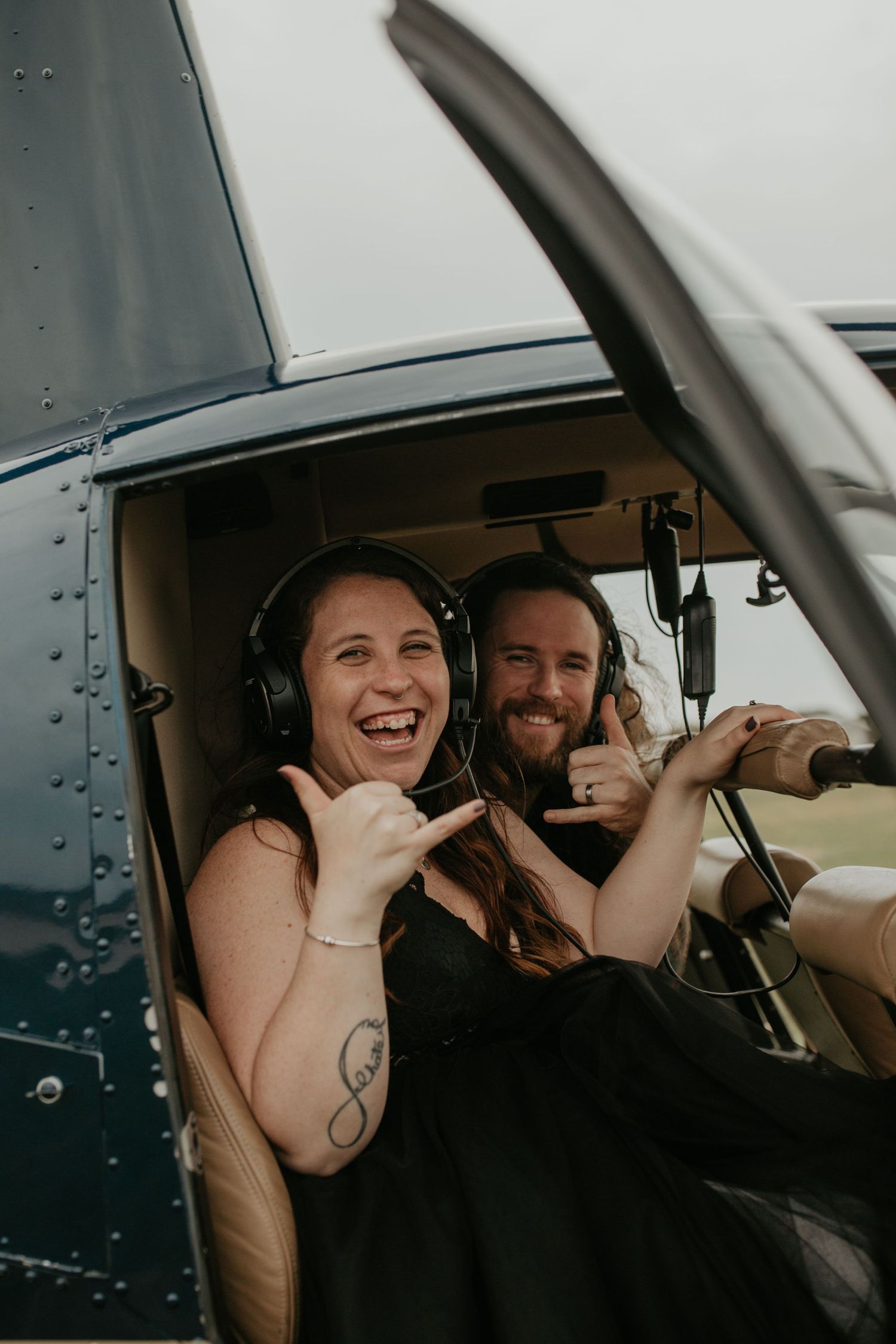 Two passengers share a joyful moment while sitting in the cockpit of a small aircraft.