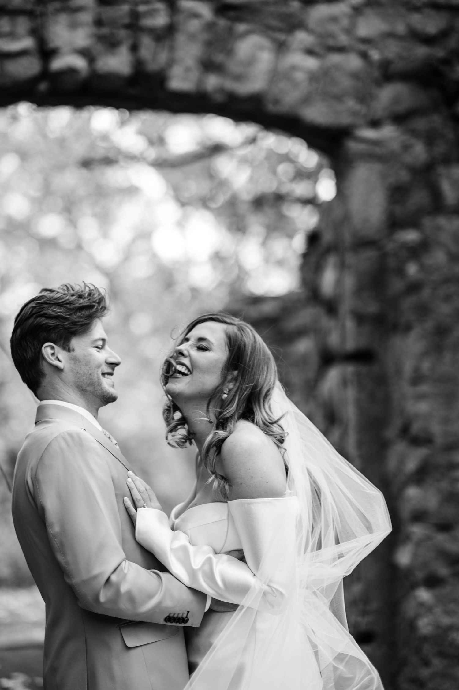 A series of black and white wedding photos showing joyful laughter and embraces between newlyweds.