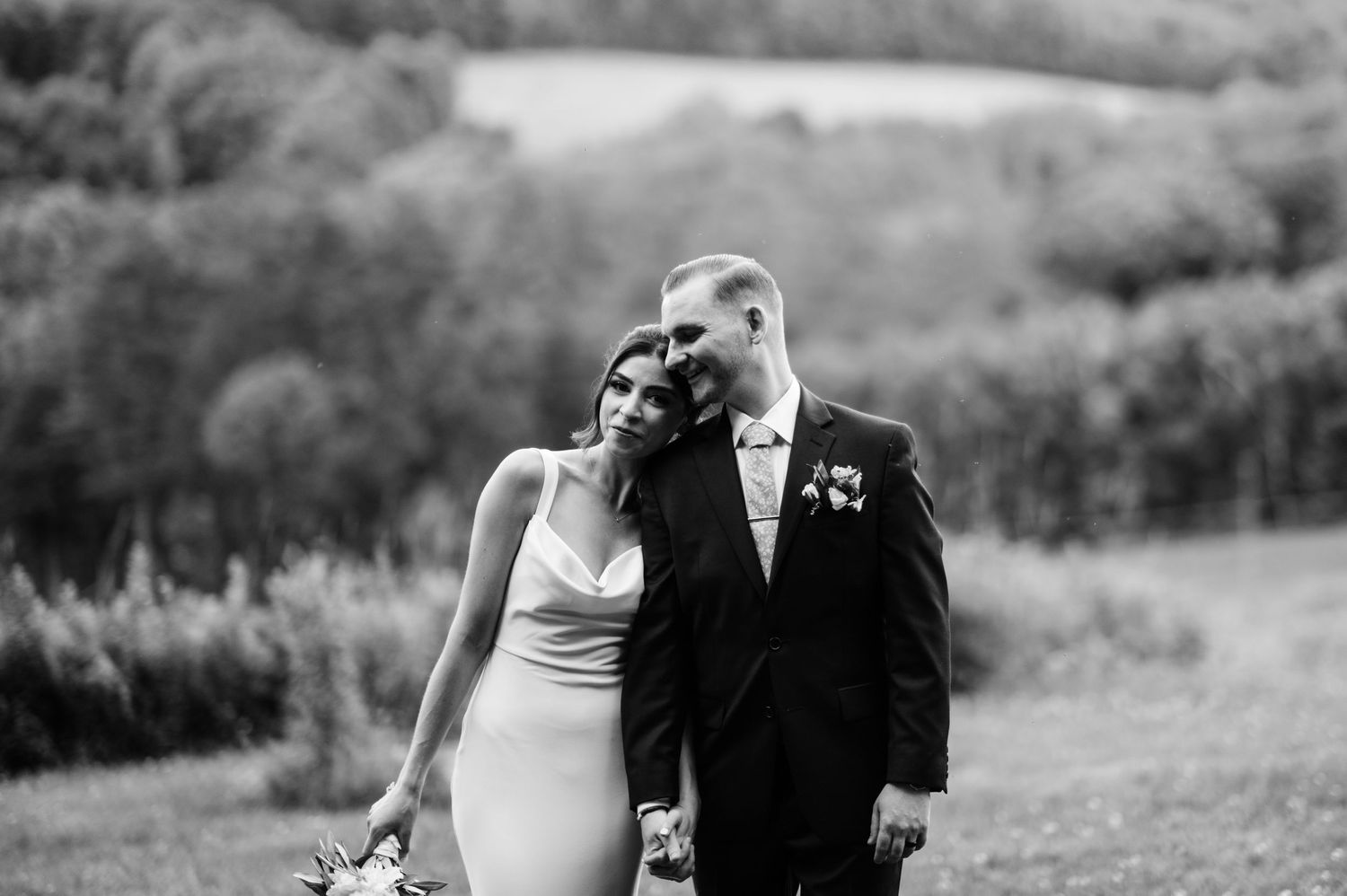 A couple walks through a scenic mountain landscape on their wedding day.