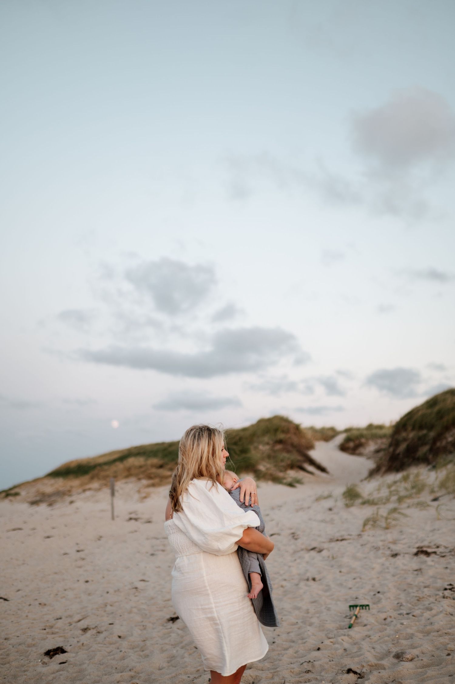 Intimate family moments captured in soft light on sandy dunes at sunset.
