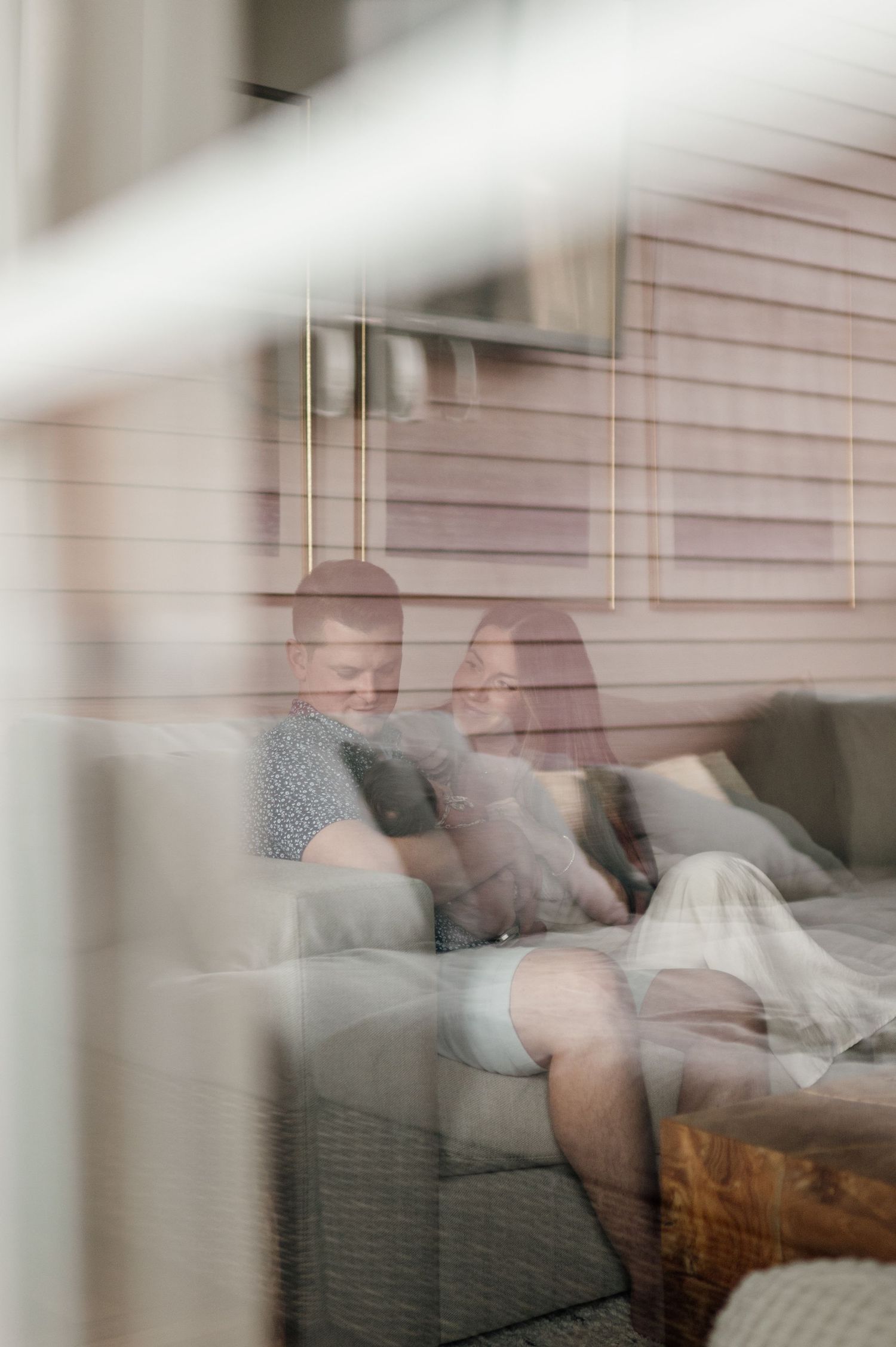 Dreamy sequence of someone resting on a couch seen through window blinds creating a soft, ethereal effect.