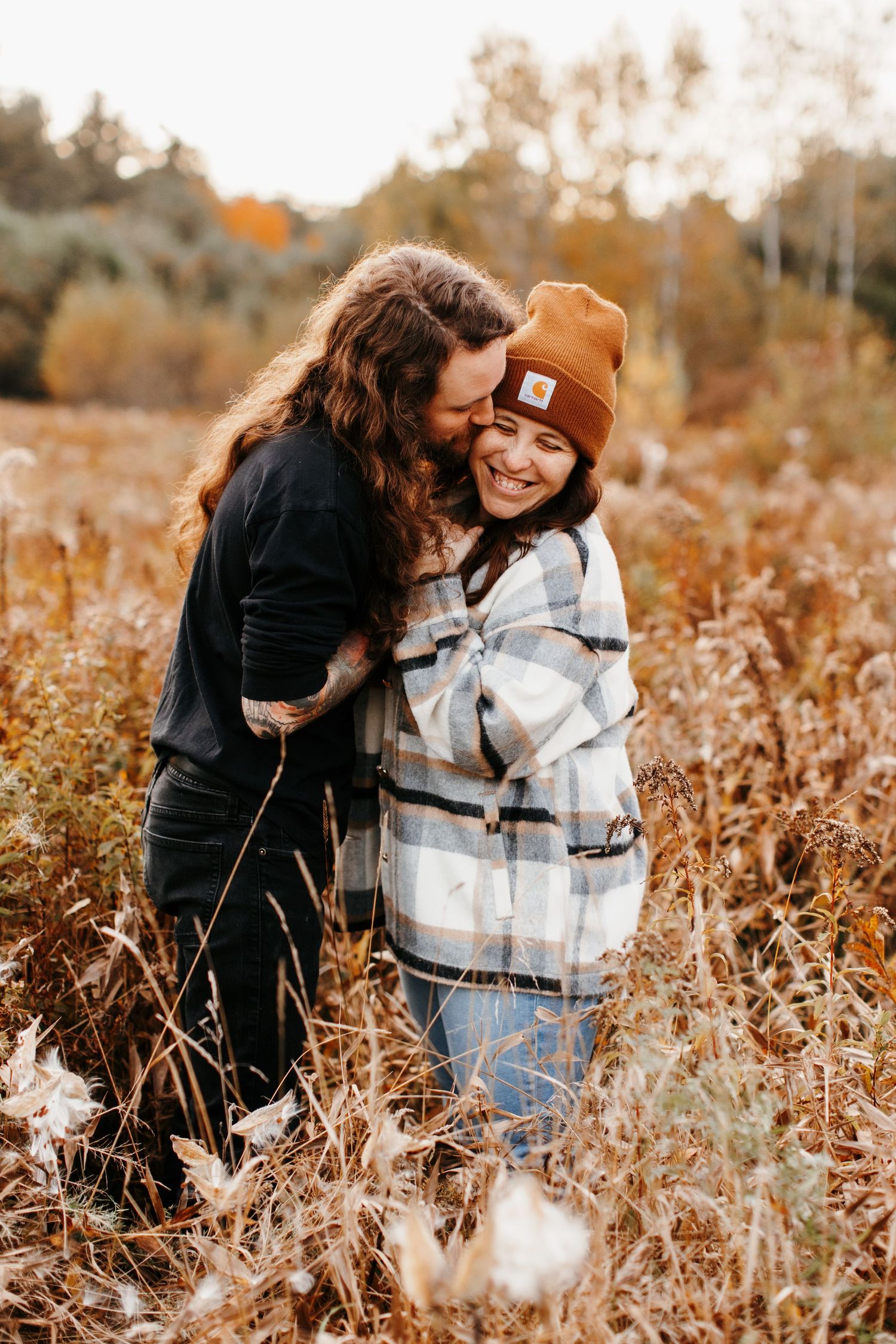 Two people share a joyful moment together in a golden autumn field during sunset.