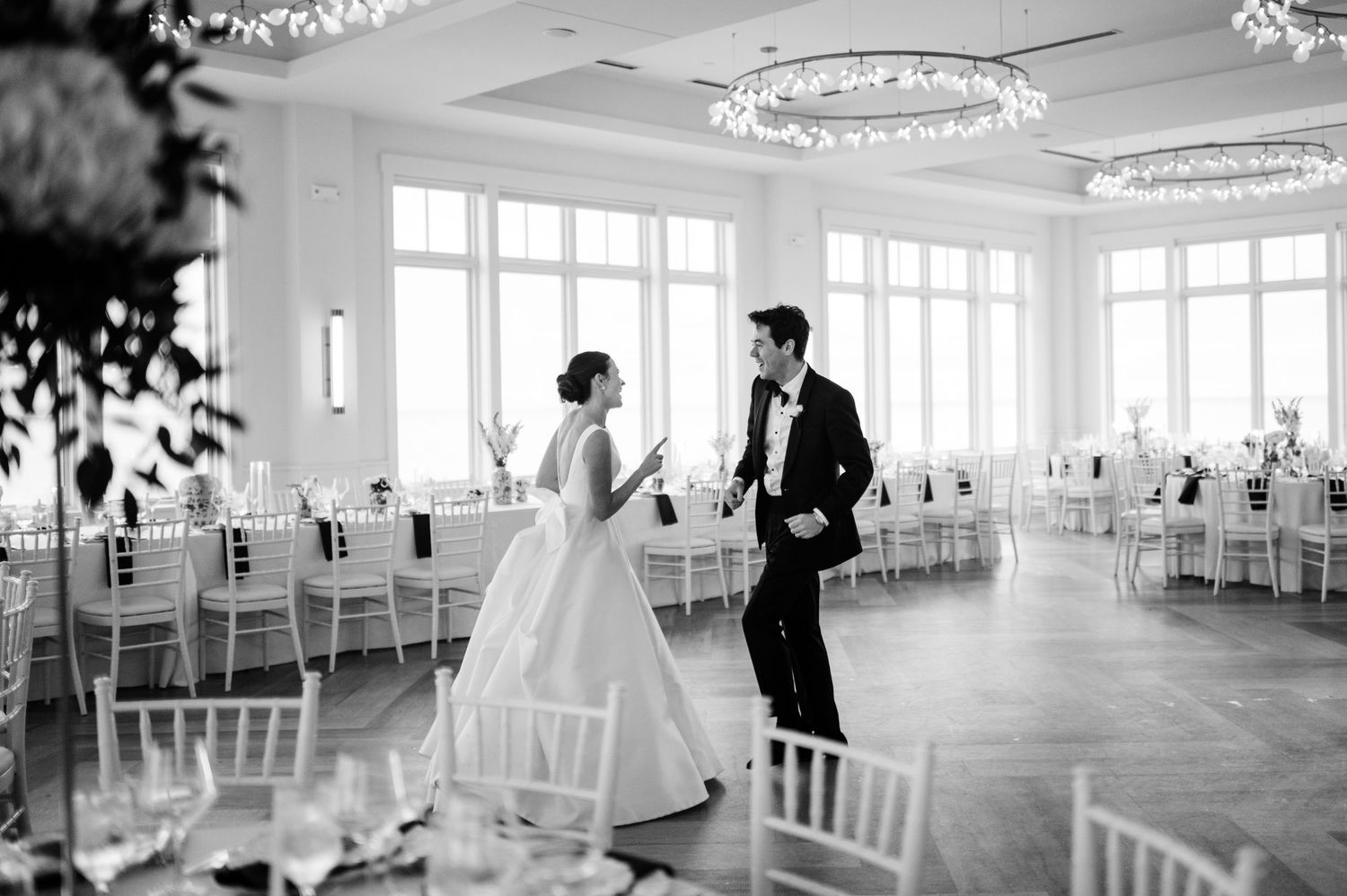 Elegant white ballroom with crystal chandeliers set up for wedding reception.