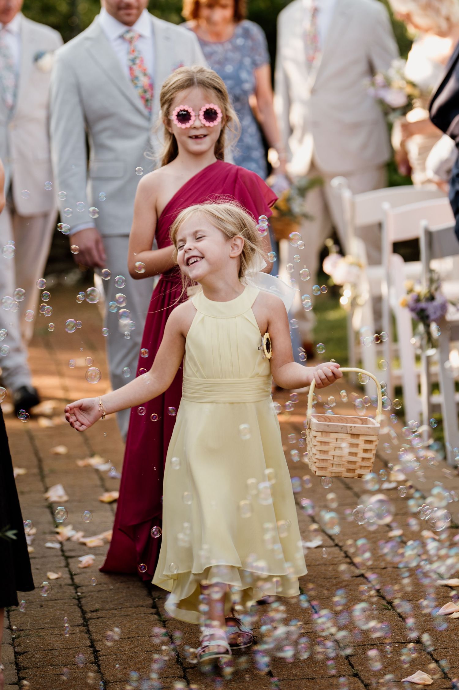 Young children play with bubbles at an outdoor wedding celebration.