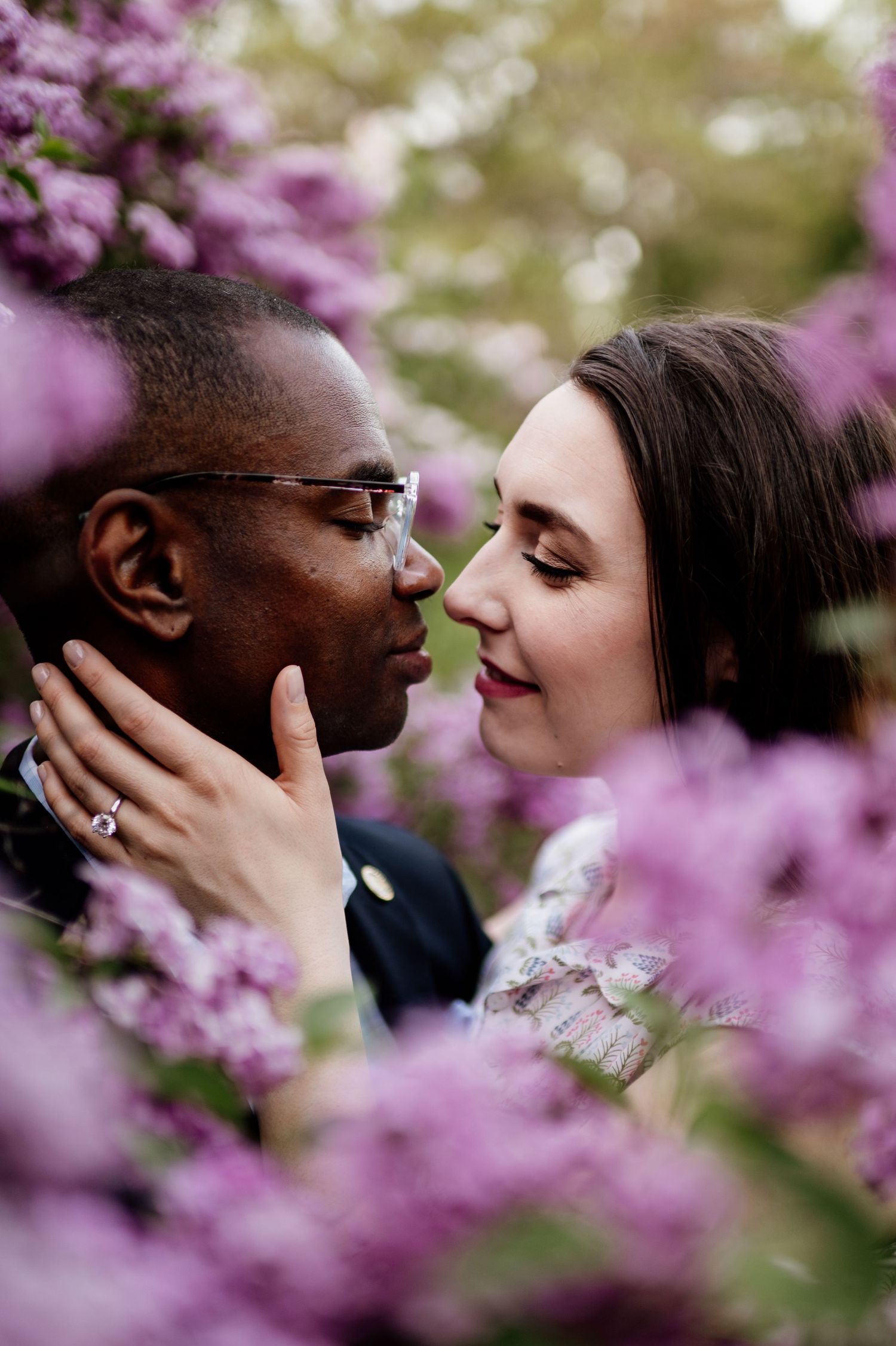 A romantic couple shares an intimate moment surrounded by blooming cherry blossoms in spring.
