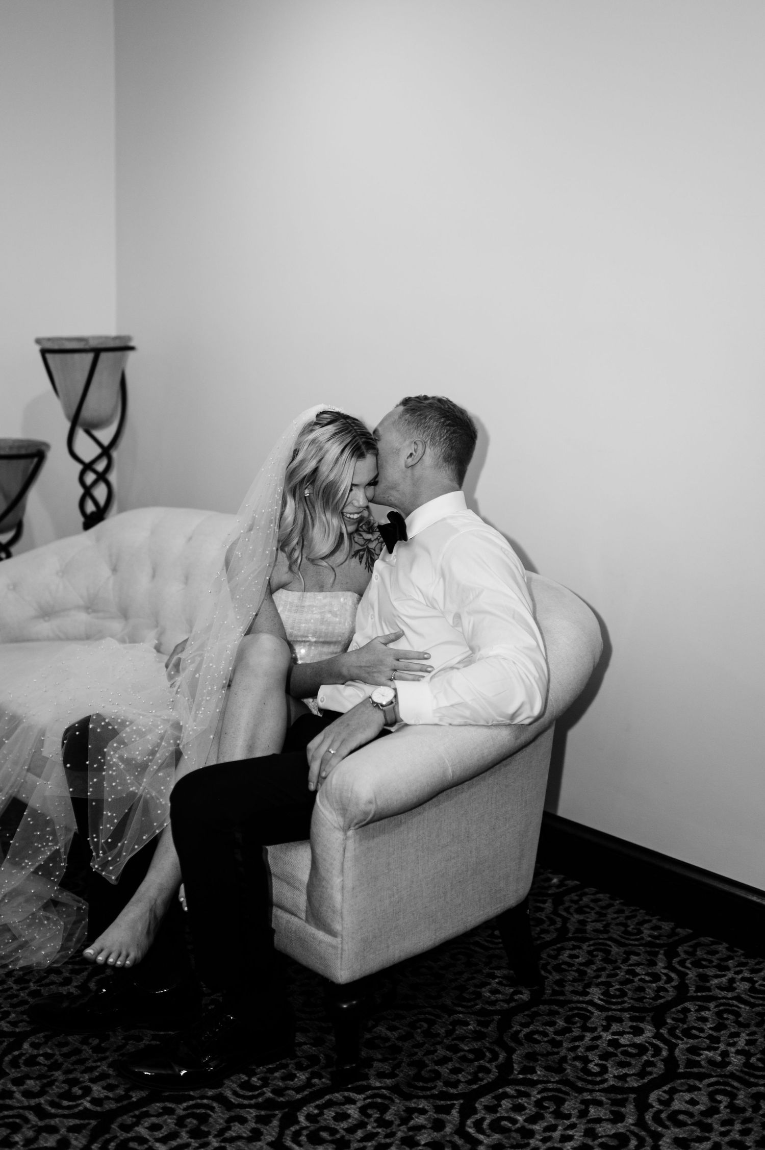 Black and white photo of a couple sharing an intimate moment on a couch.