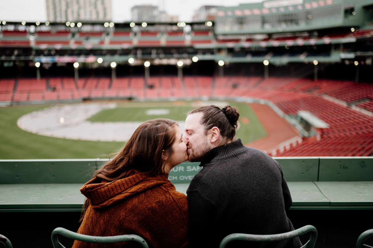 A romantic moment captured at an empty baseball stadium during golden hour.