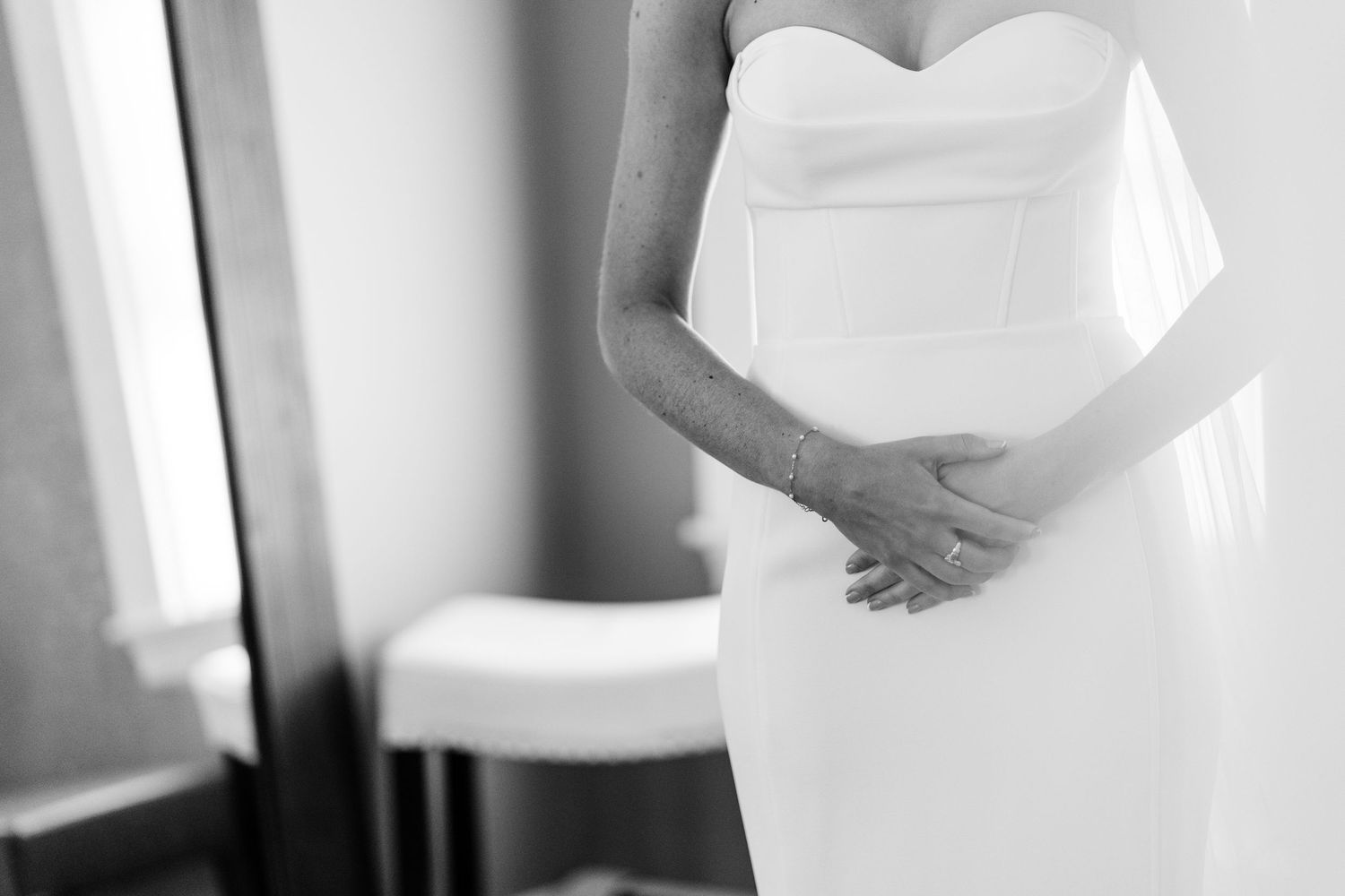 Close-up details of white wedding dress against light background.
