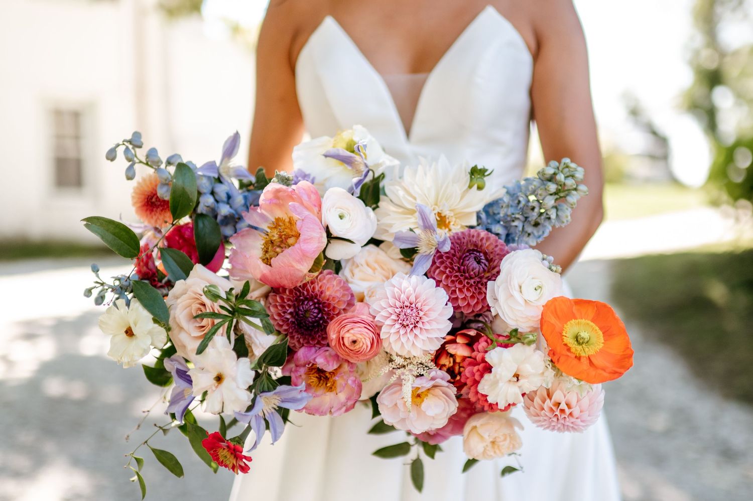 Vibrant wedding bouquets featuring dahlias, roses, and ranunculus in coral, pink, and orange tones against a light background.
