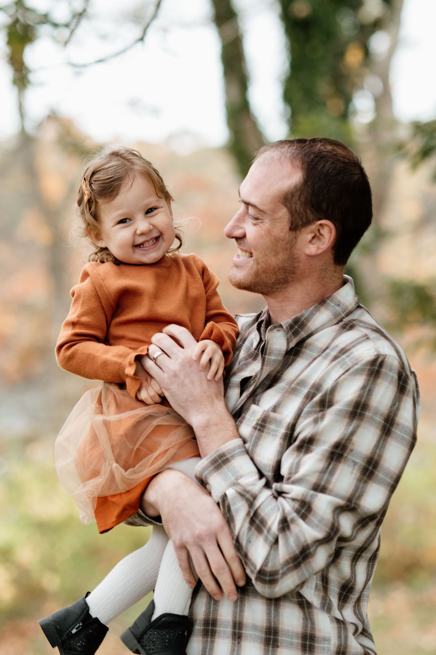 Parent and child sharing joyful moments outdoors in autumn setting.