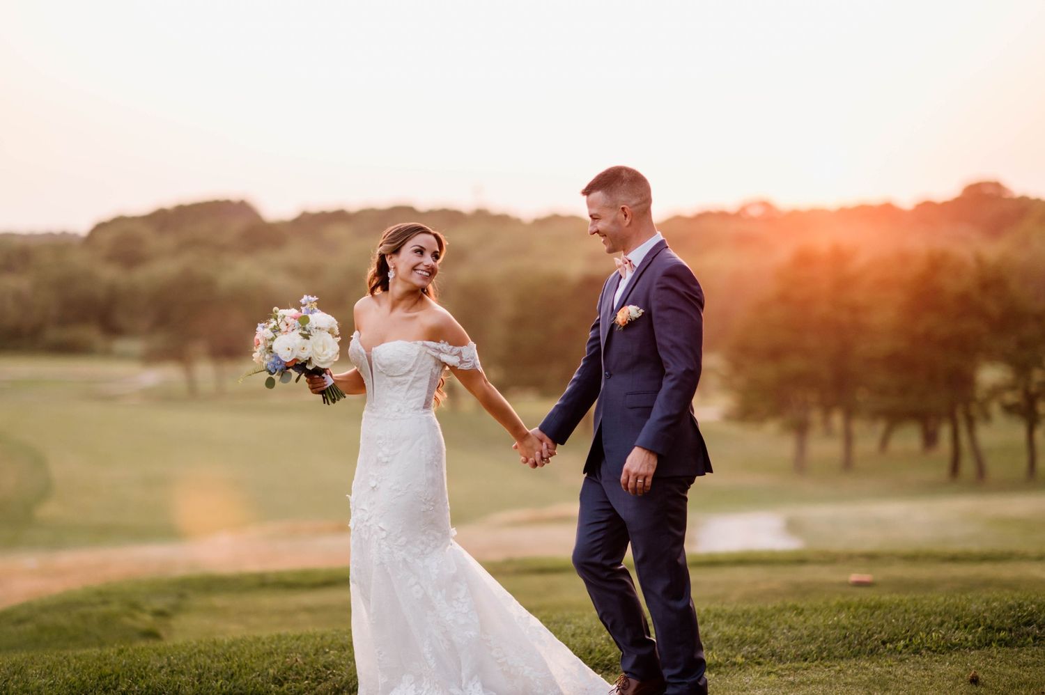 A couple dances together during sunset in an outdoor wedding celebration.