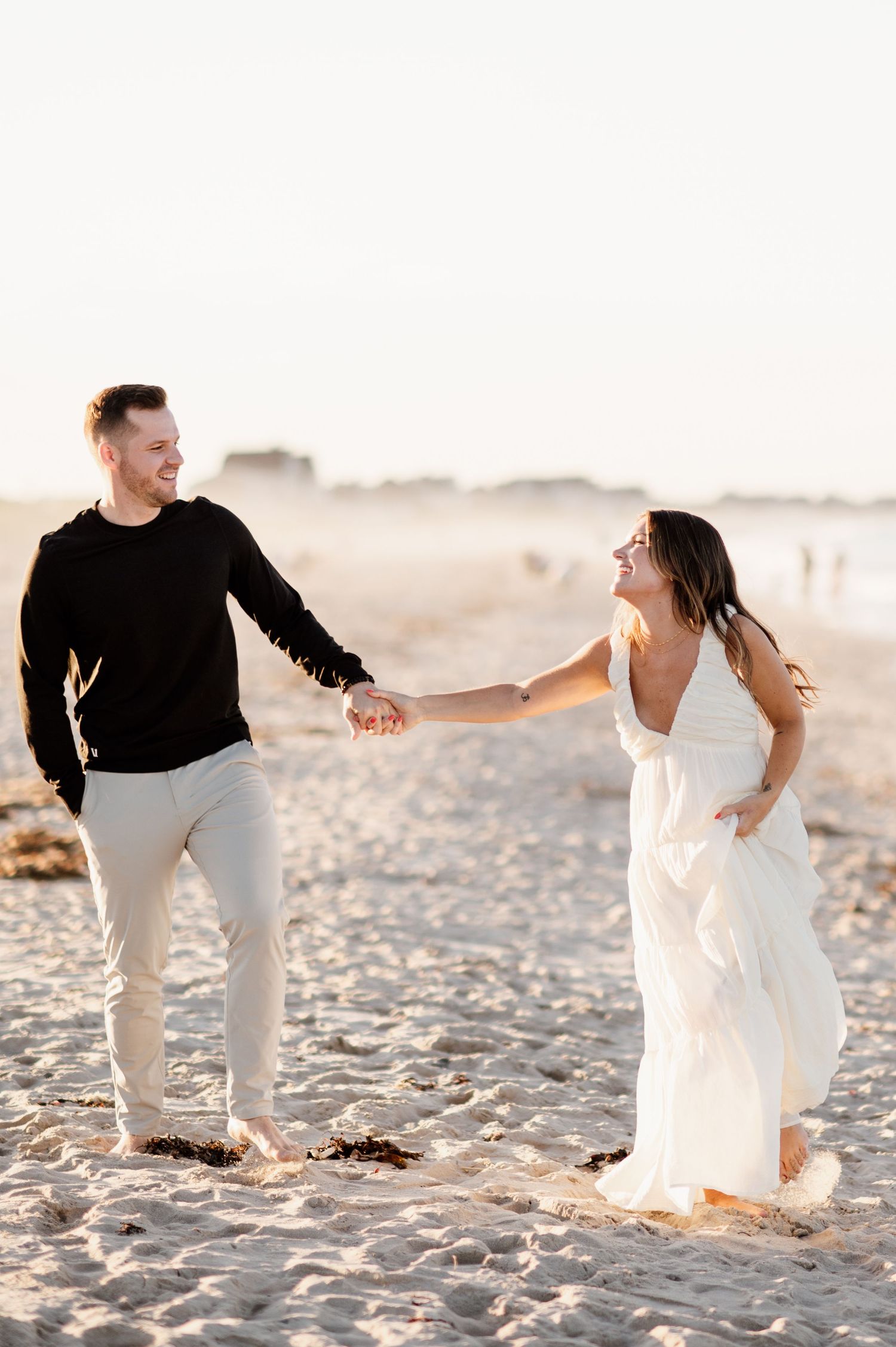 Romantic couple dancing together on a sandy beach at sunset.