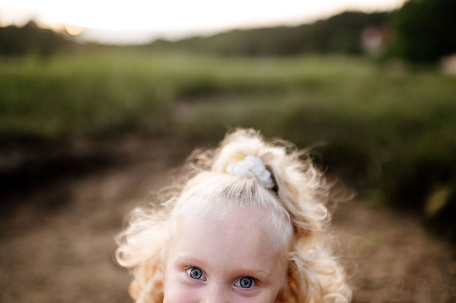 A young child walks along a sandy path surrounded by lush greenery.