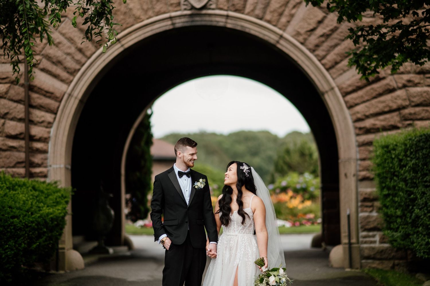 A wedding couple poses beneath stone archways for romantic portraits.