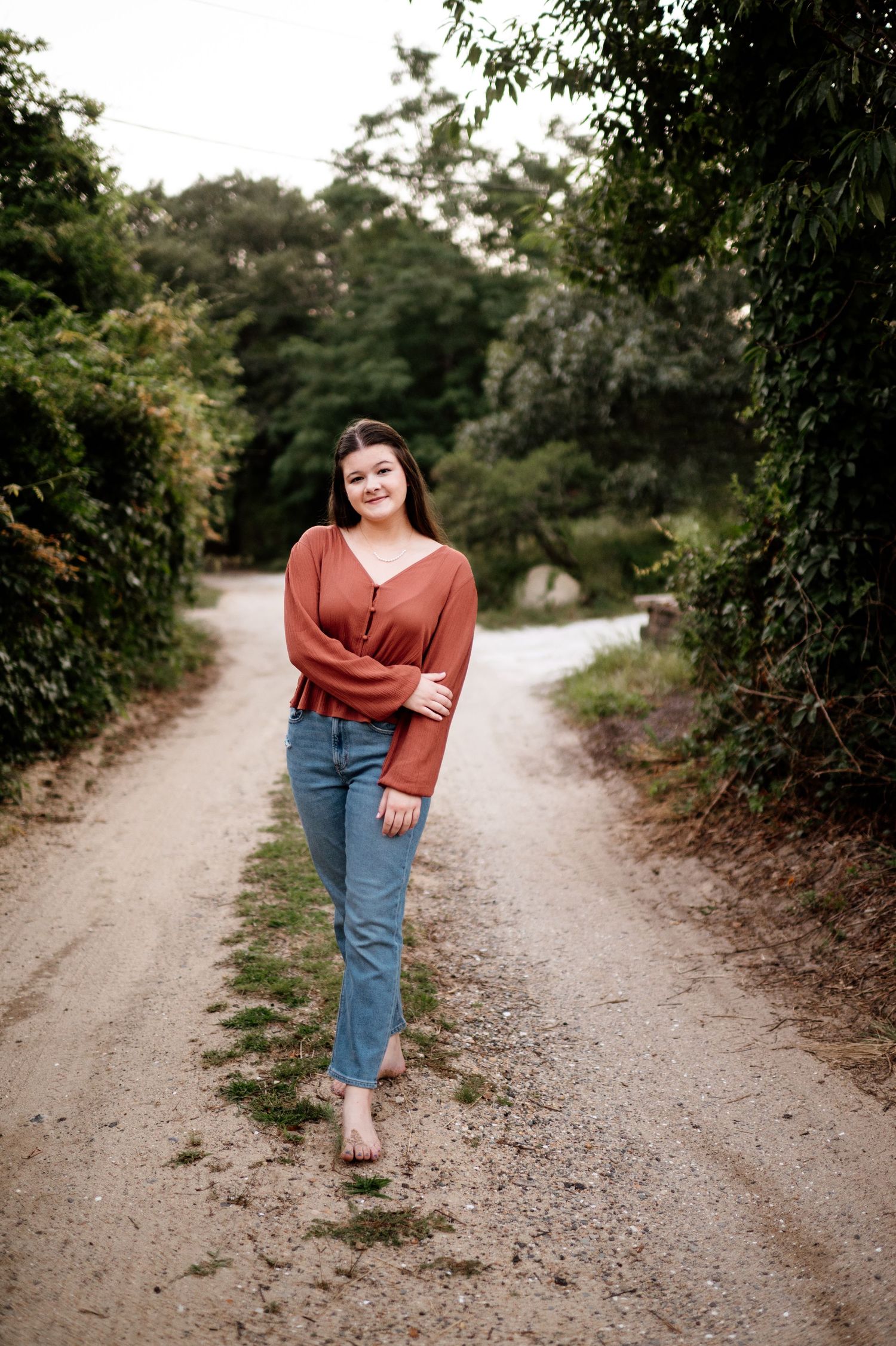 Casual outdoor photoshoot on a gravel path surrounded by lush green foliage.