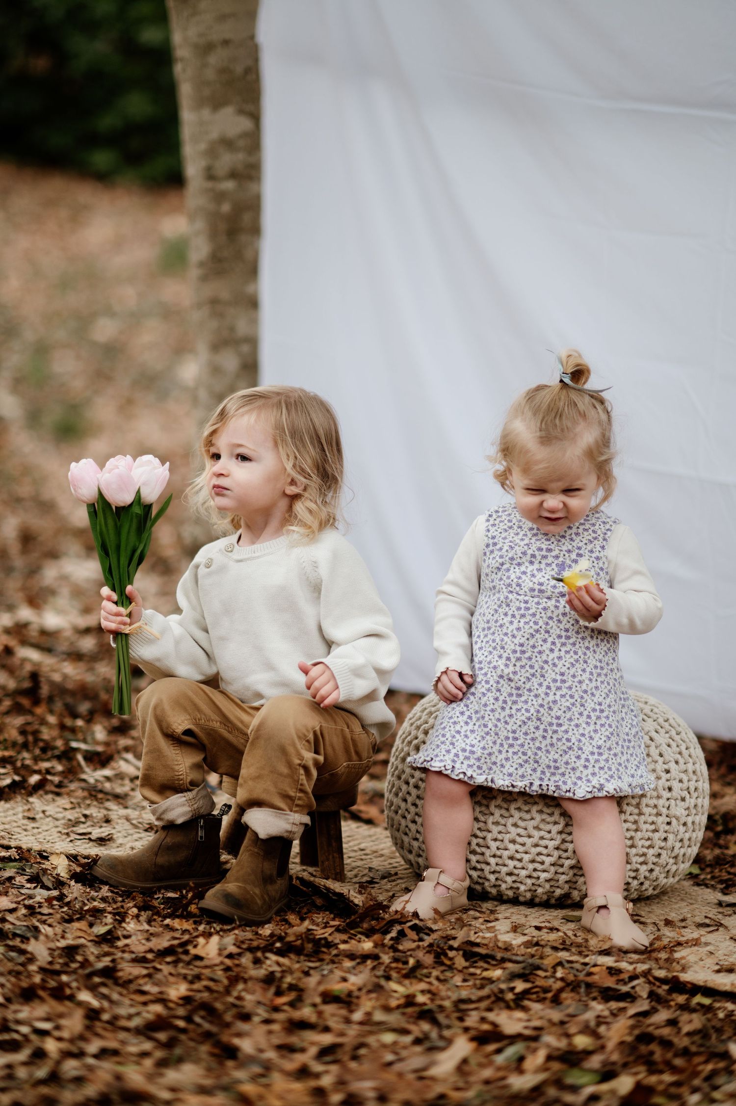 Series of toddlers sitting on cushions with flowers against white backdrop.