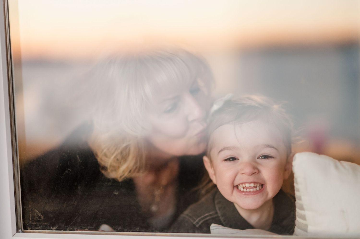 Candid reflection in window glass showing joyful expressions during sunset.