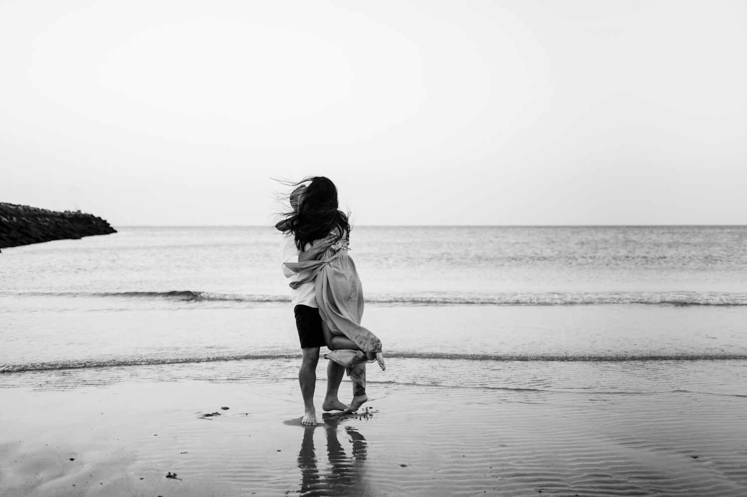 Minimalist black and white beach photos showing couple's silhouettes against ocean backdrop.