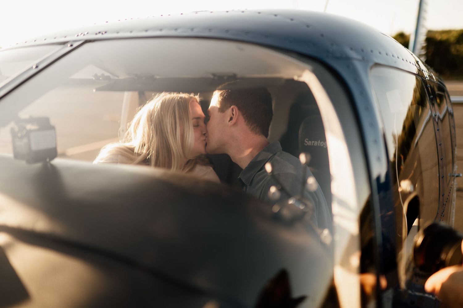 A romantic couple shares an intimate moment in a car during sunset.