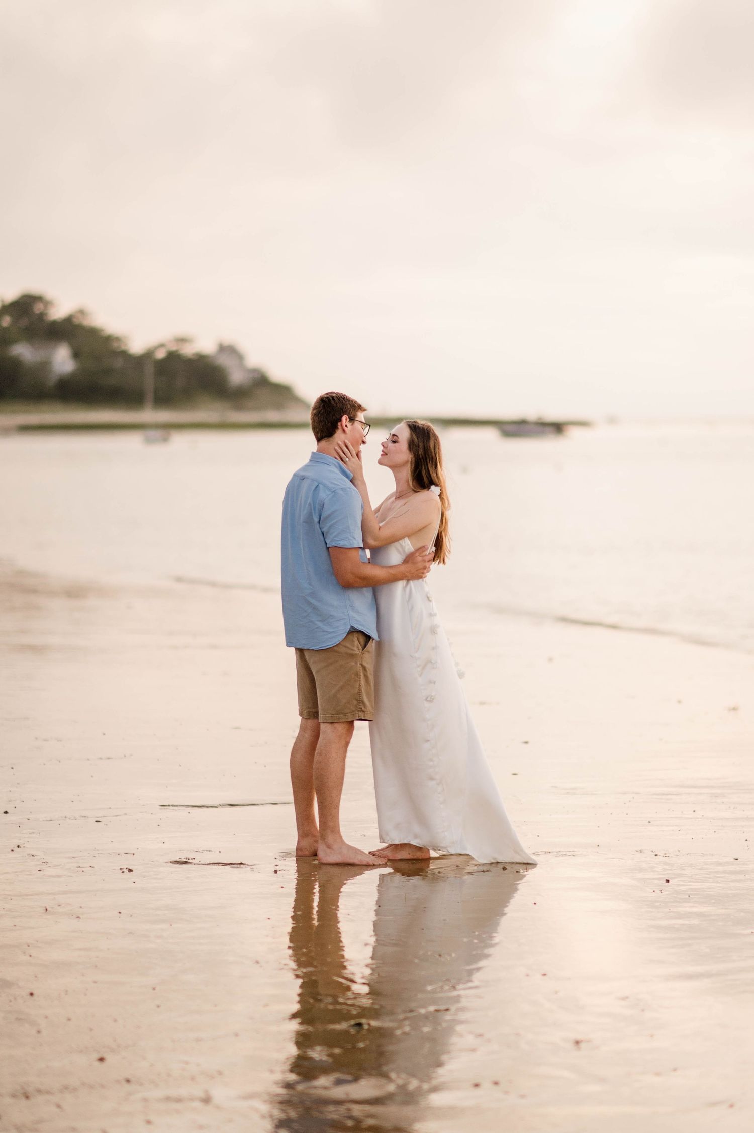 Couple sharing a romantic moment while standing in shallow ocean water at sunset.
