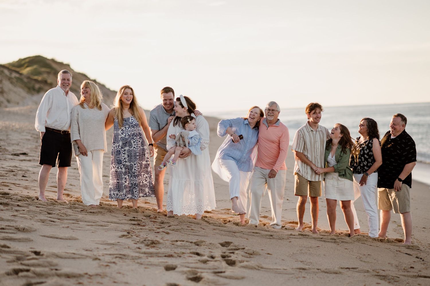 A group walking together along a sandy beach at sunset creating a silhouetted line against the horizon.