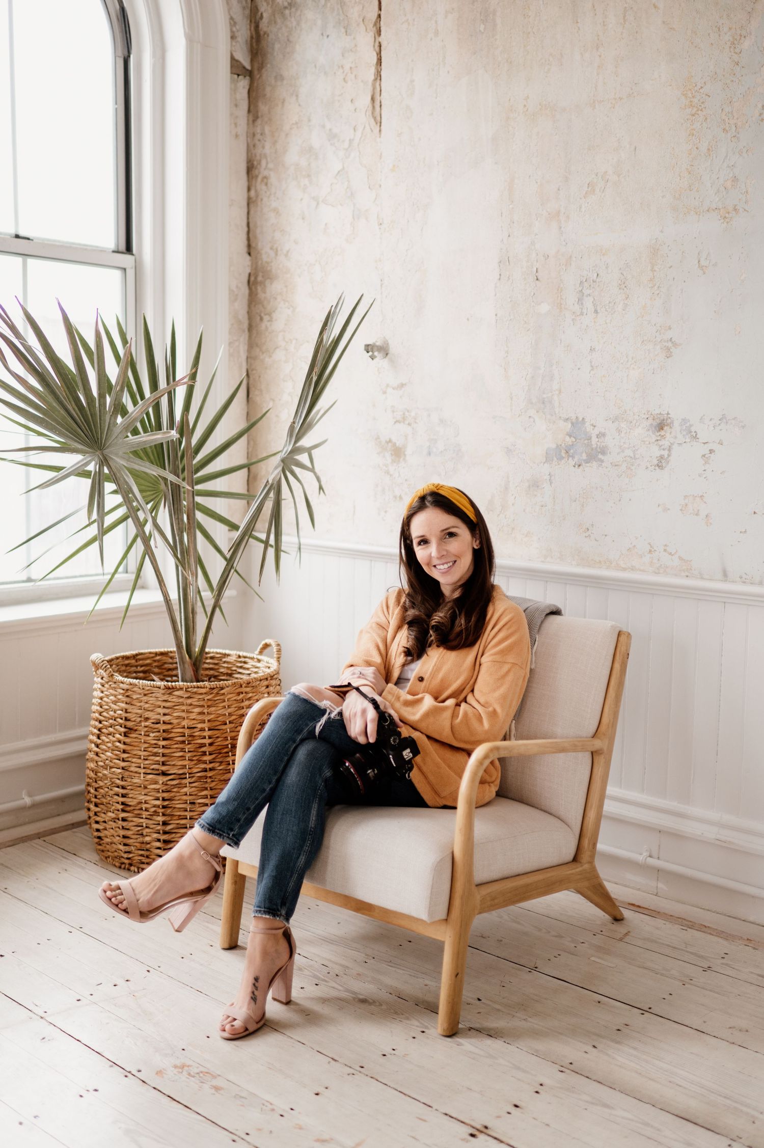 Lifestyle photos in a bright minimalist room with wooden chair, woven basket, and potted palm plant.