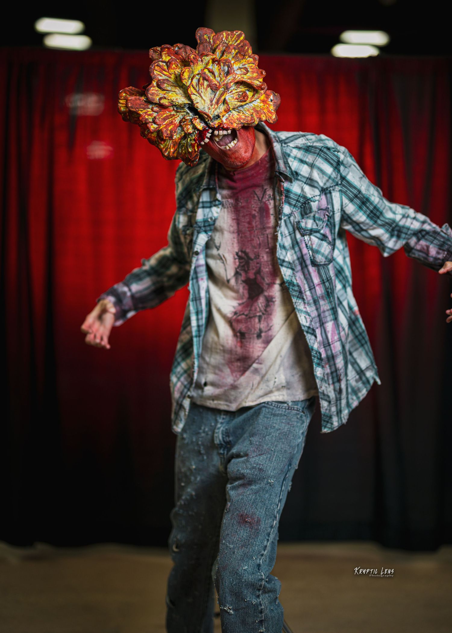 Horror costume featuring plaid shirt and bloody makeup against red curtain background.