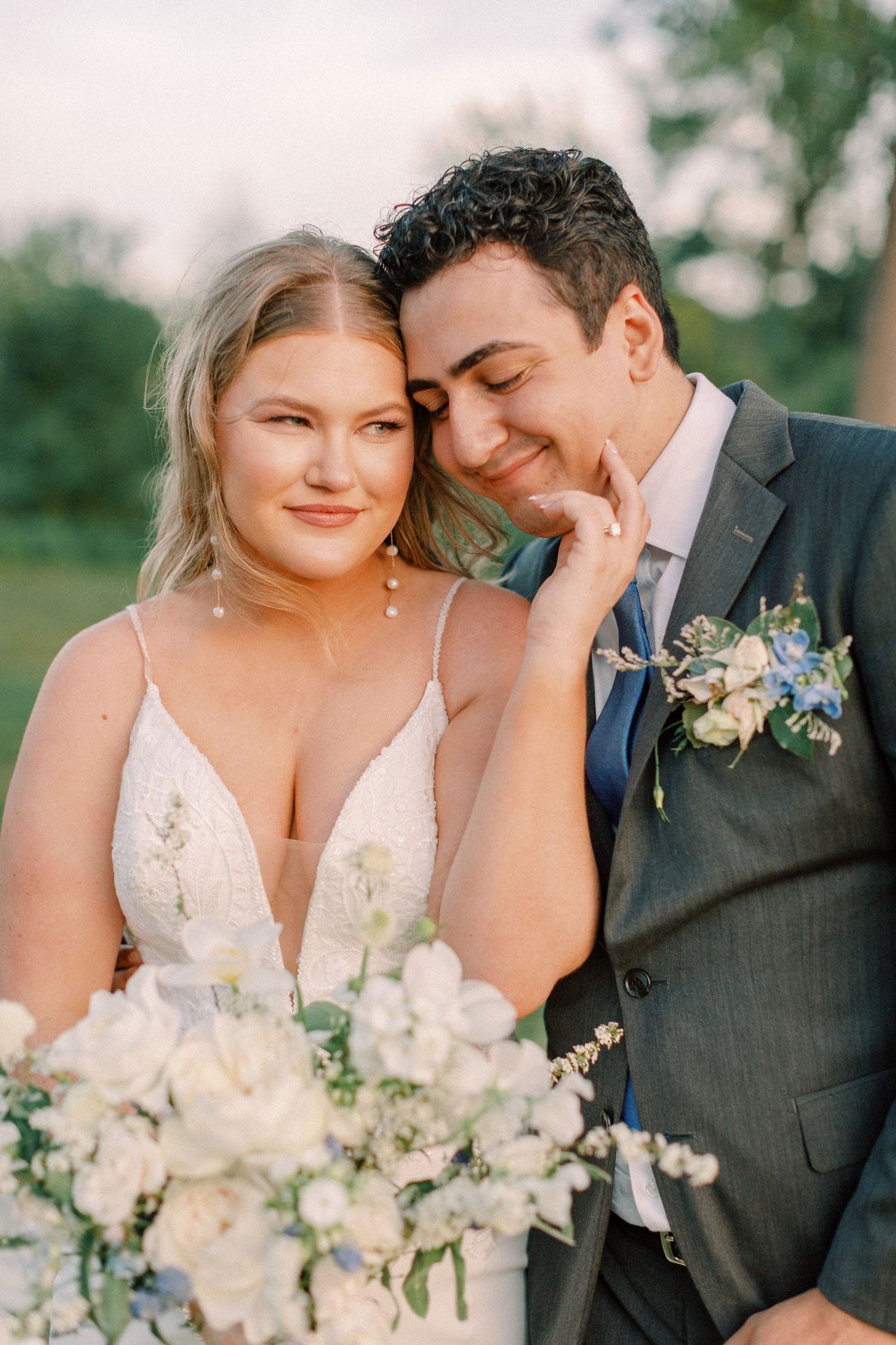 Close-up portrait of newlyweds sharing an intimate moment with white bouquet.