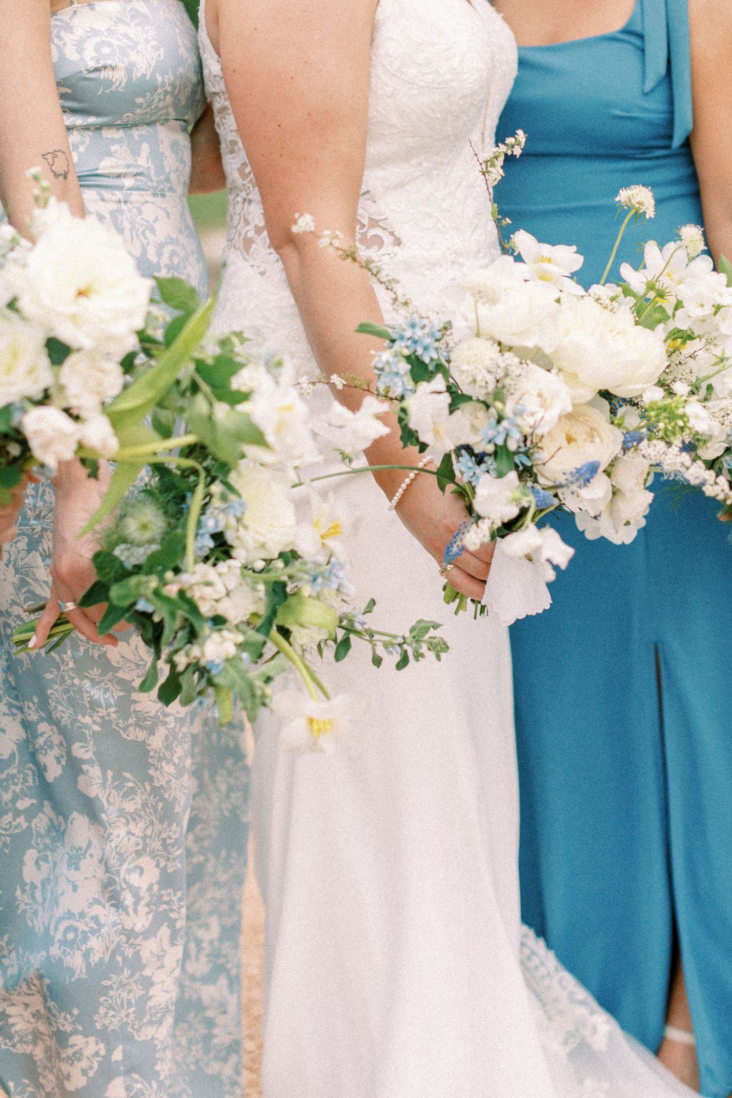 Detail shot of bridesmaids holding white bouquets against blue dresses.