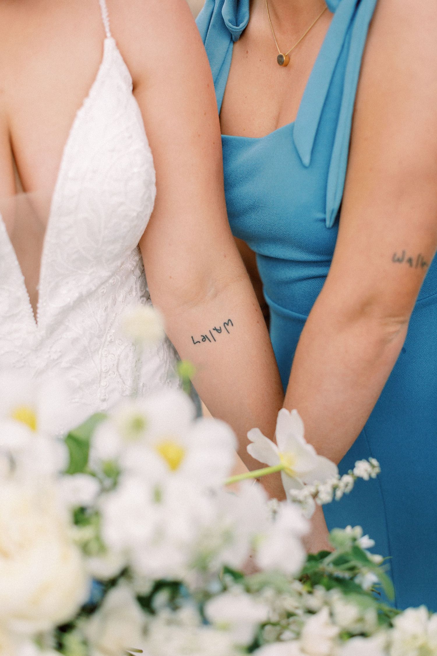 Close-up of bridesmaids holding white floral bouquets showing matching blue dresses.