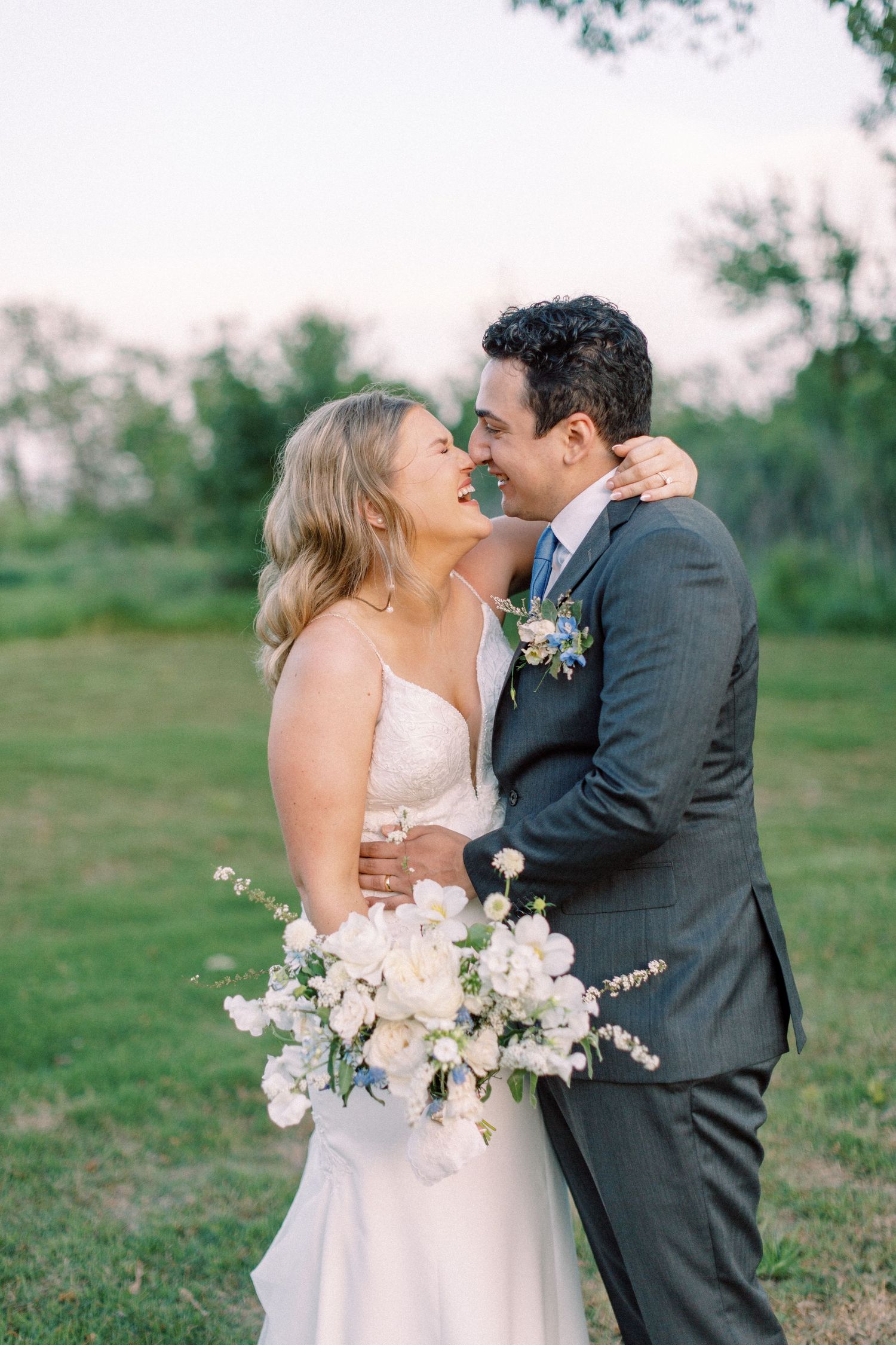 Newlyweds share a romantic moment outdoors with white floral bouquet.