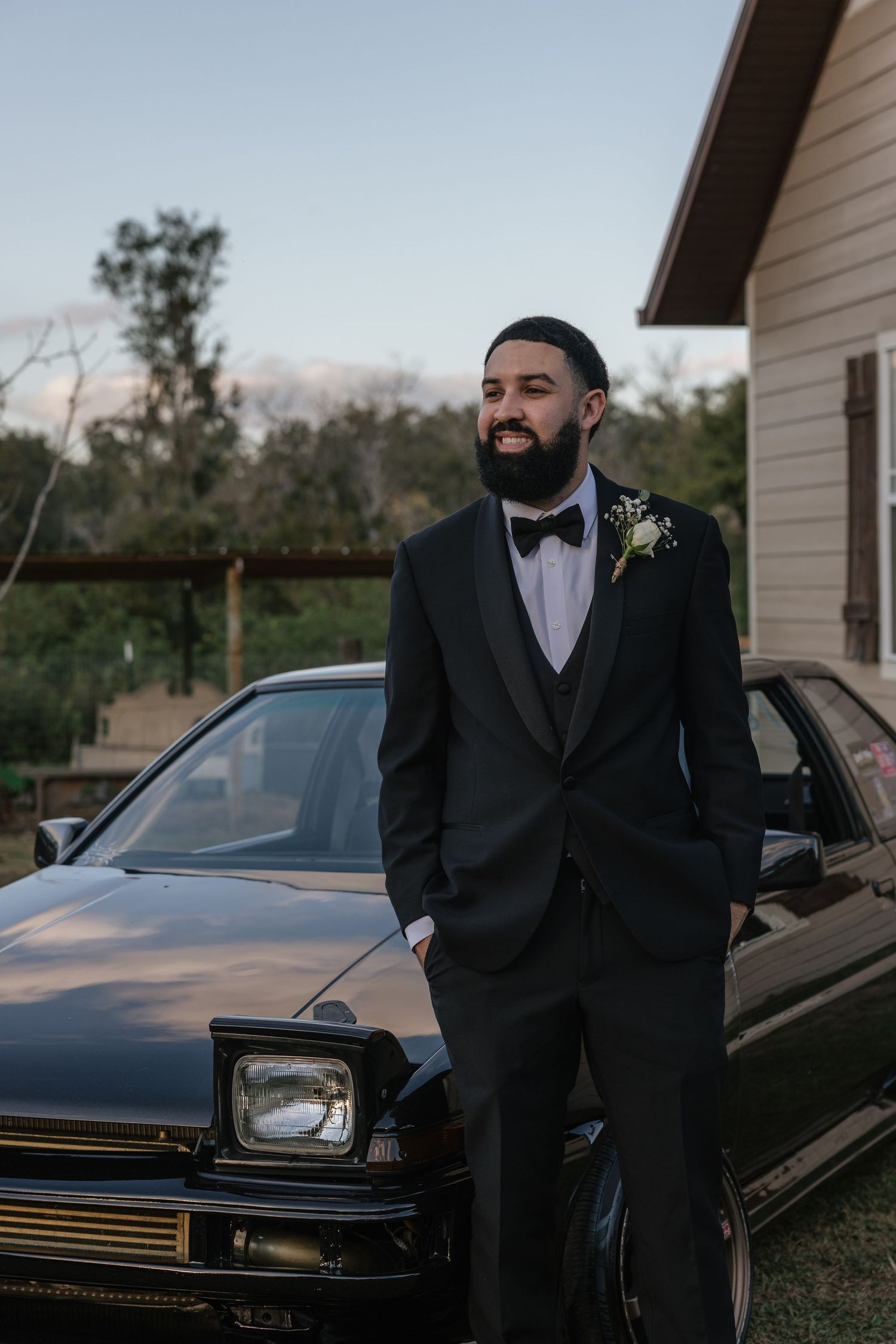 Formal wedding attire and black car captured in outdoor setting.