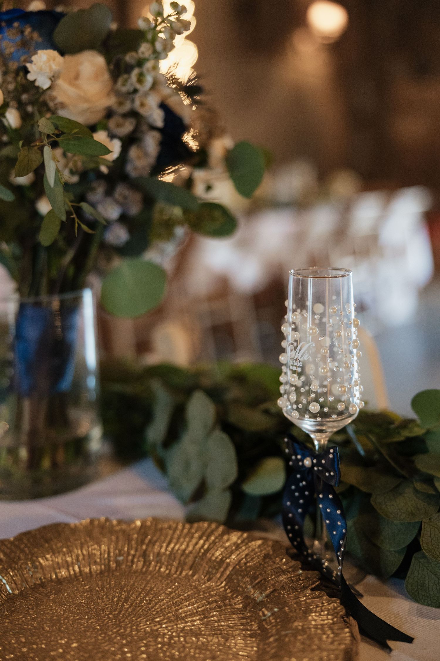 Elegant wedding reception table setting with gold charger plates and floral centerpieces.