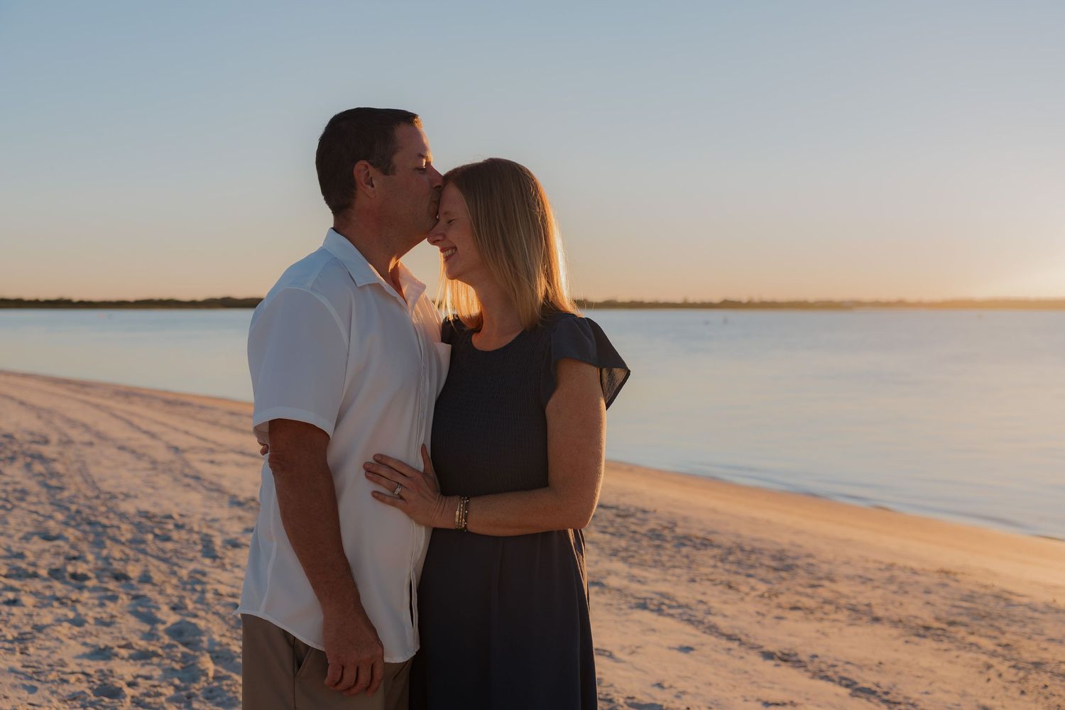 Romantic couple sharing tender moment on beach during golden hour.