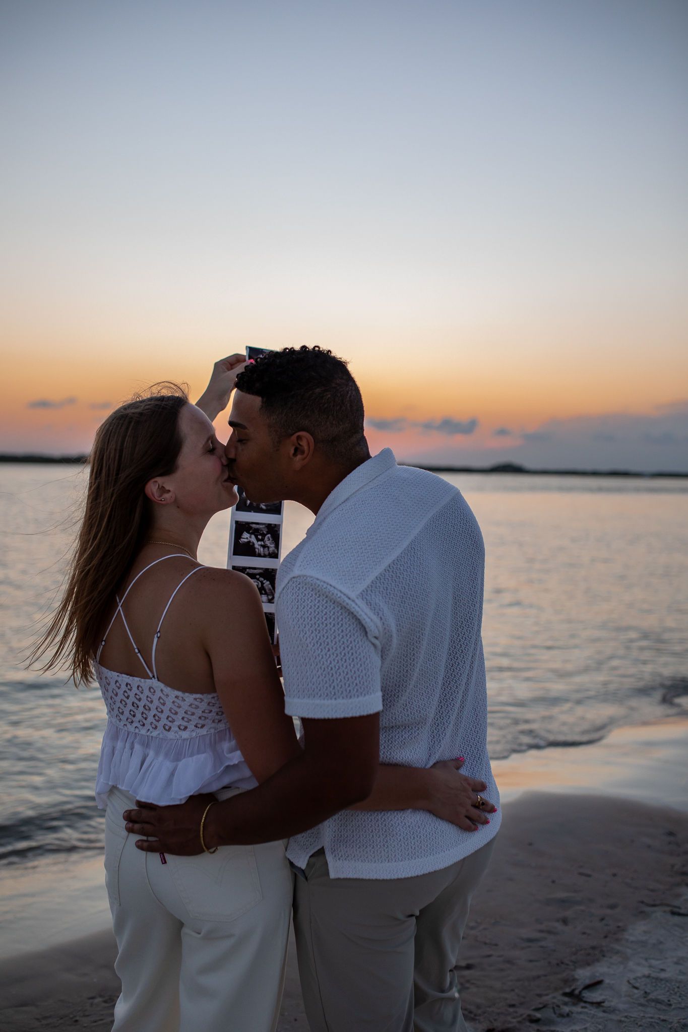 Silhouetted couple sharing intimate moment at sunset beach.