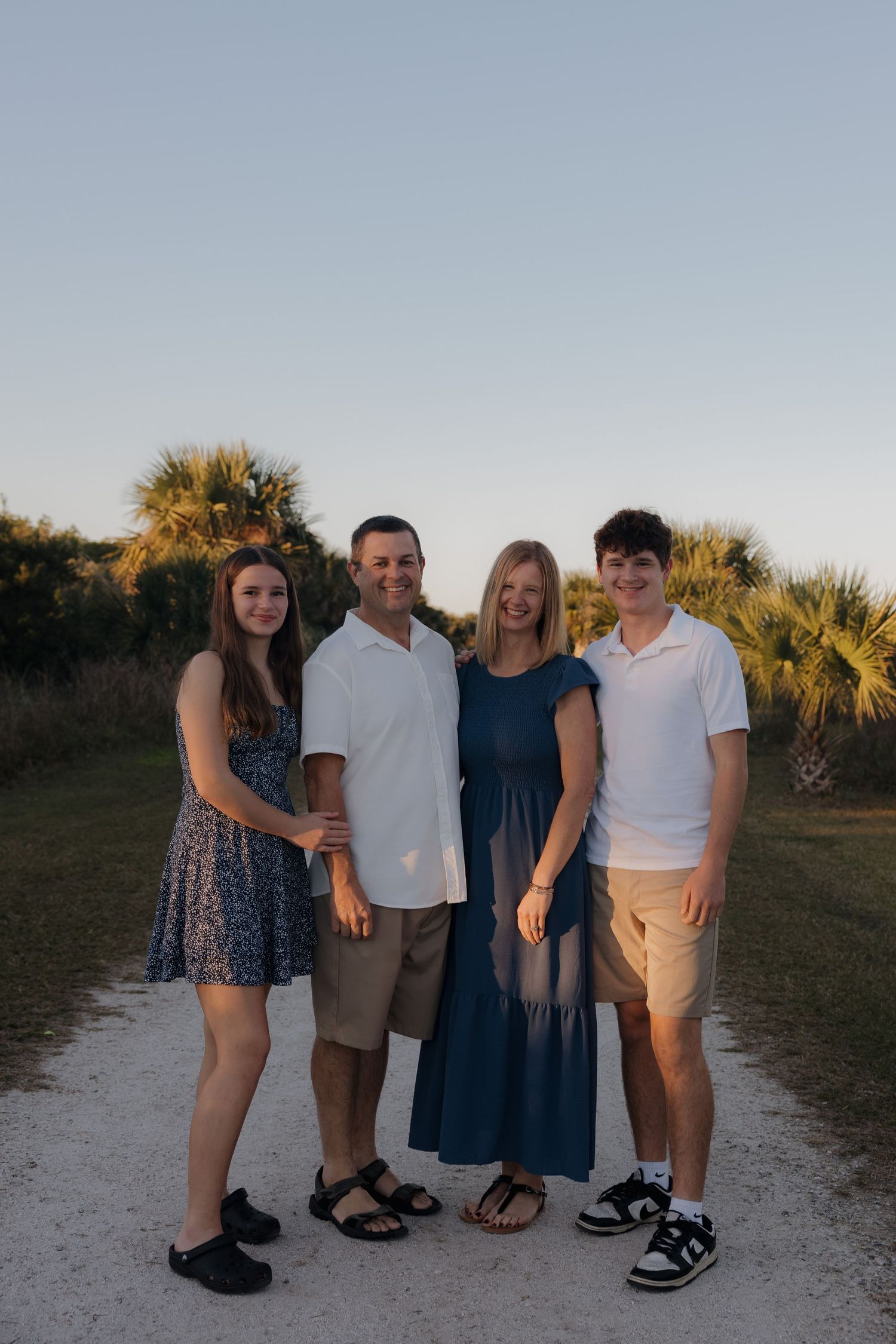 A family group poses together at sunset on a sandy beach path.