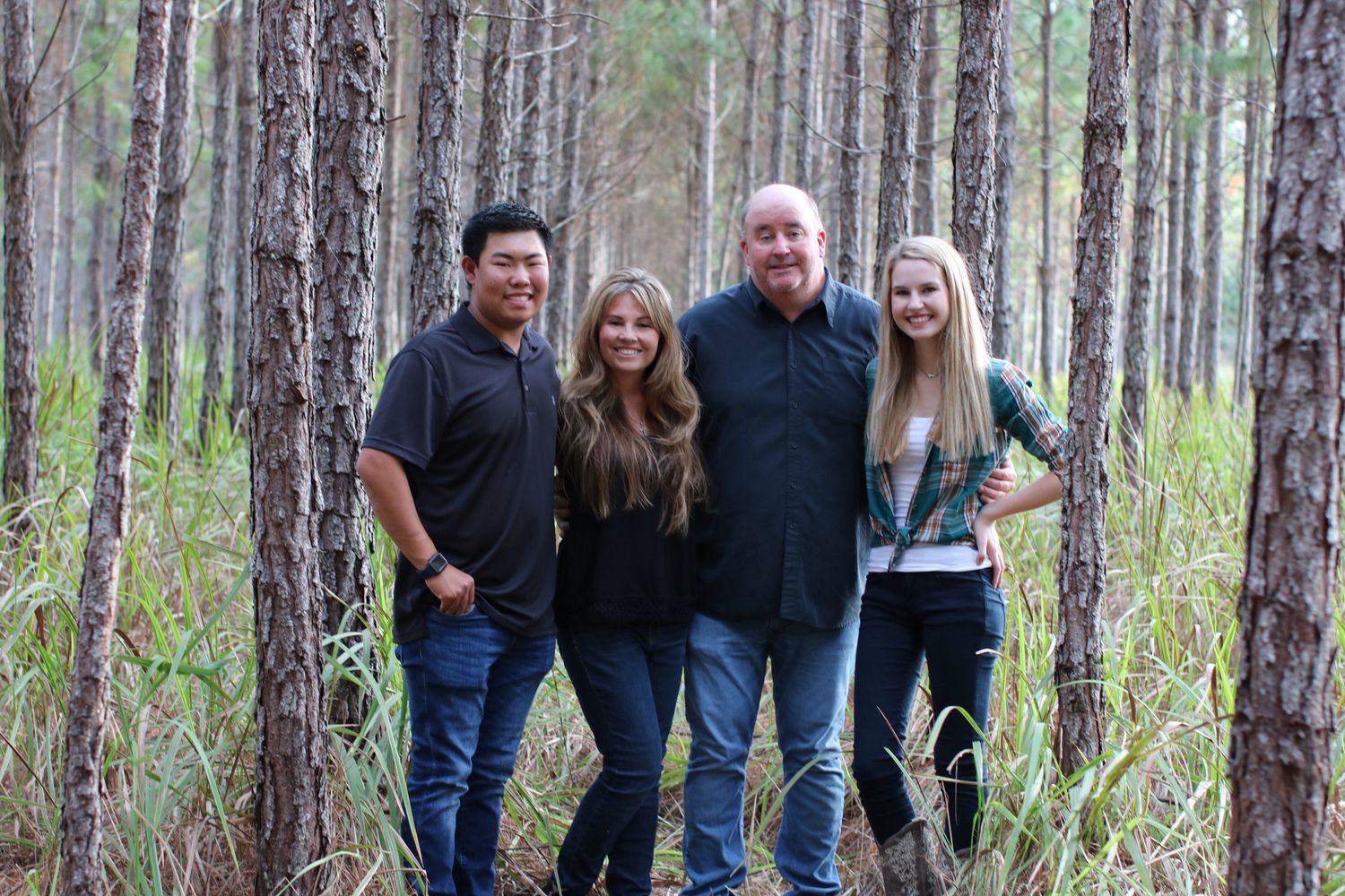 Casual group photo shoot among tall pine trees in a peaceful forest setting.