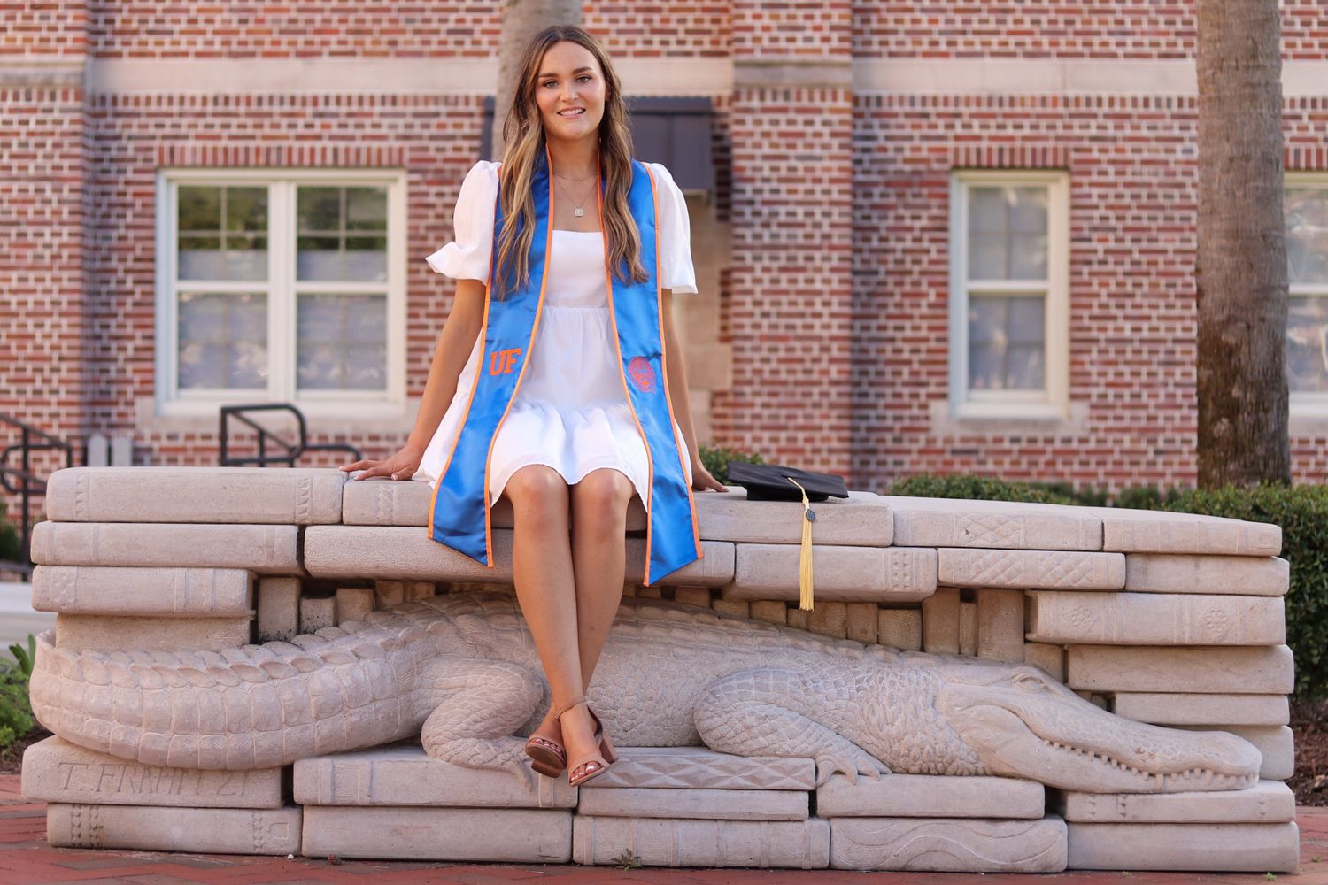 White dress and blue jacket outfit styled against brick building backdrop.