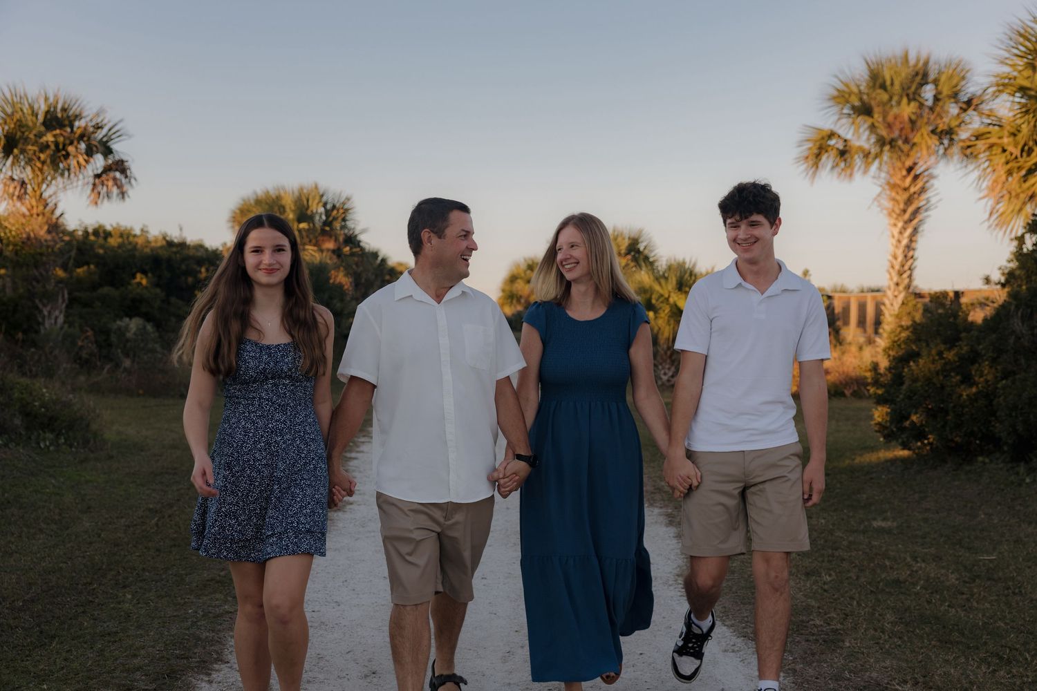 A group poses together at sunset with palm trees in the background.