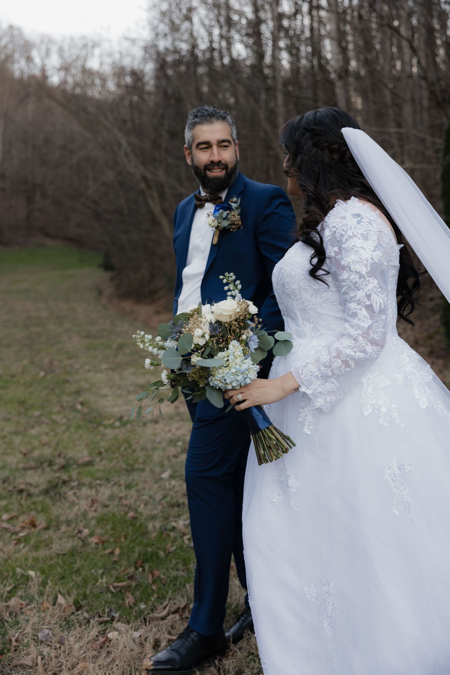 Wedding couple posing in a field with natural winter landscape backdrop.
