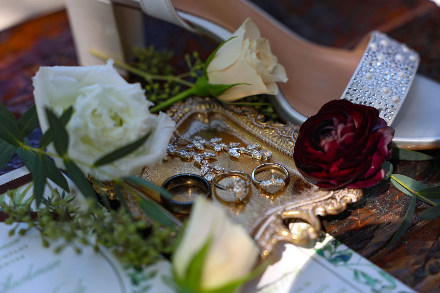 Wedding detail shots of rings, flowers, and decorative elements on rustic wooden surface.
