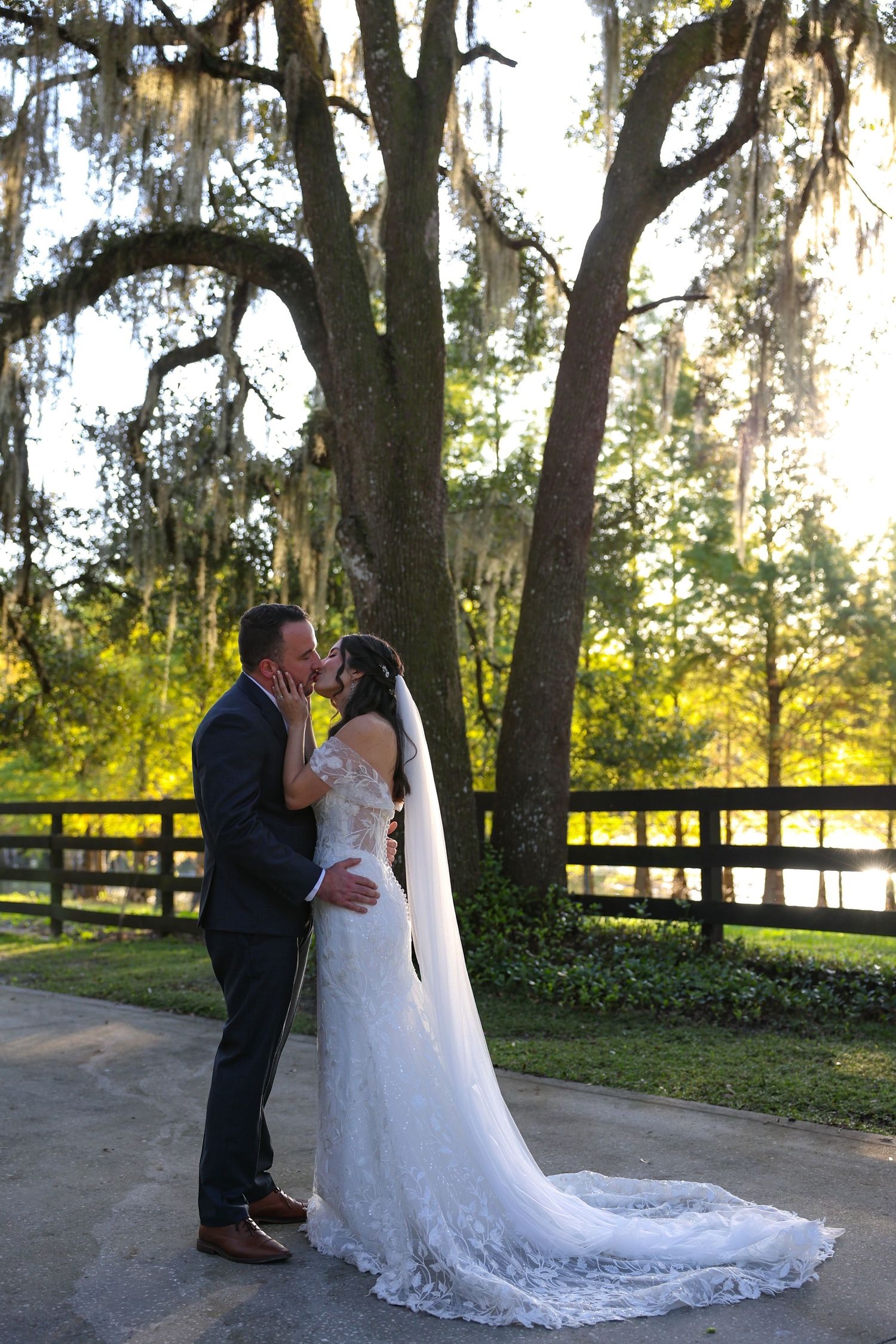 Couple shares romantic moment during sunset wedding photoshoot under moss-draped trees.