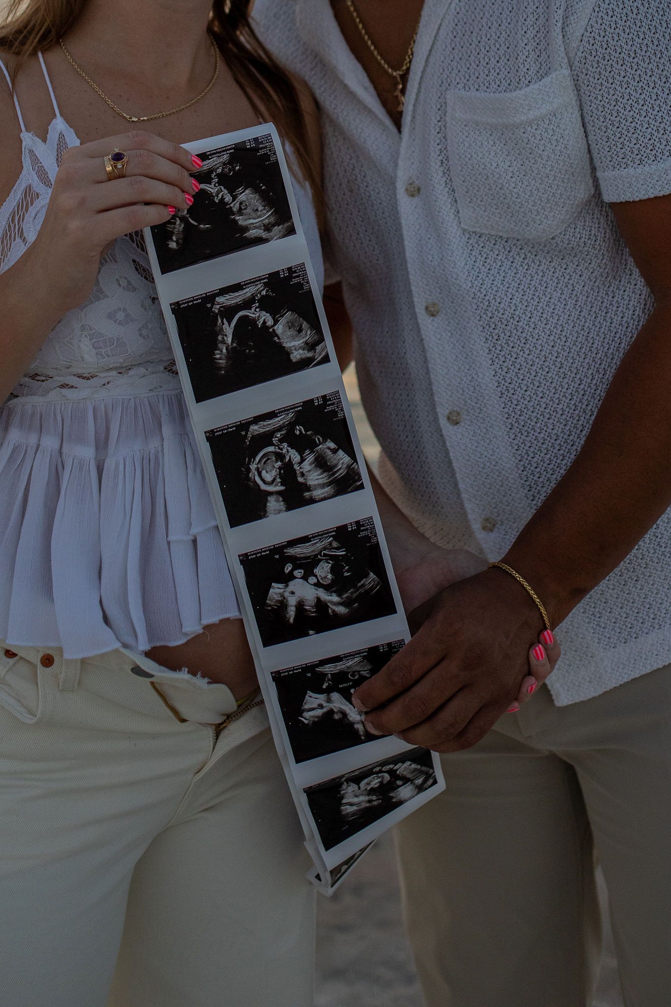 A series of ultrasound photos being held against white clothing in a pregnancy announcement sequence.