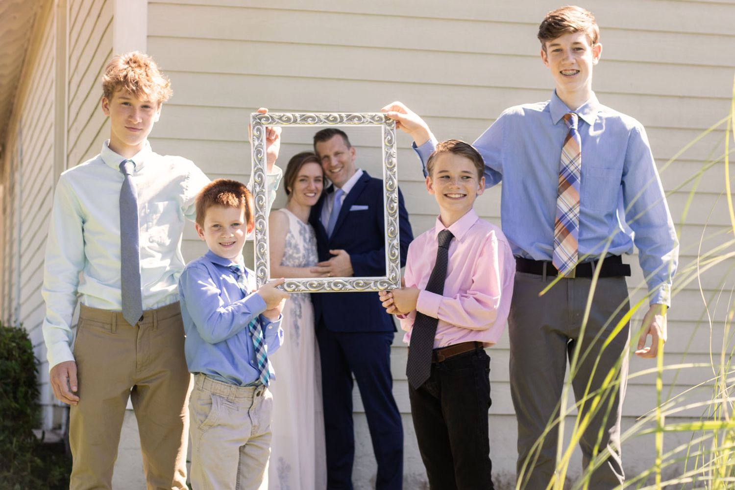 Outdoor family gathering with people lined up against a white house exterior.
