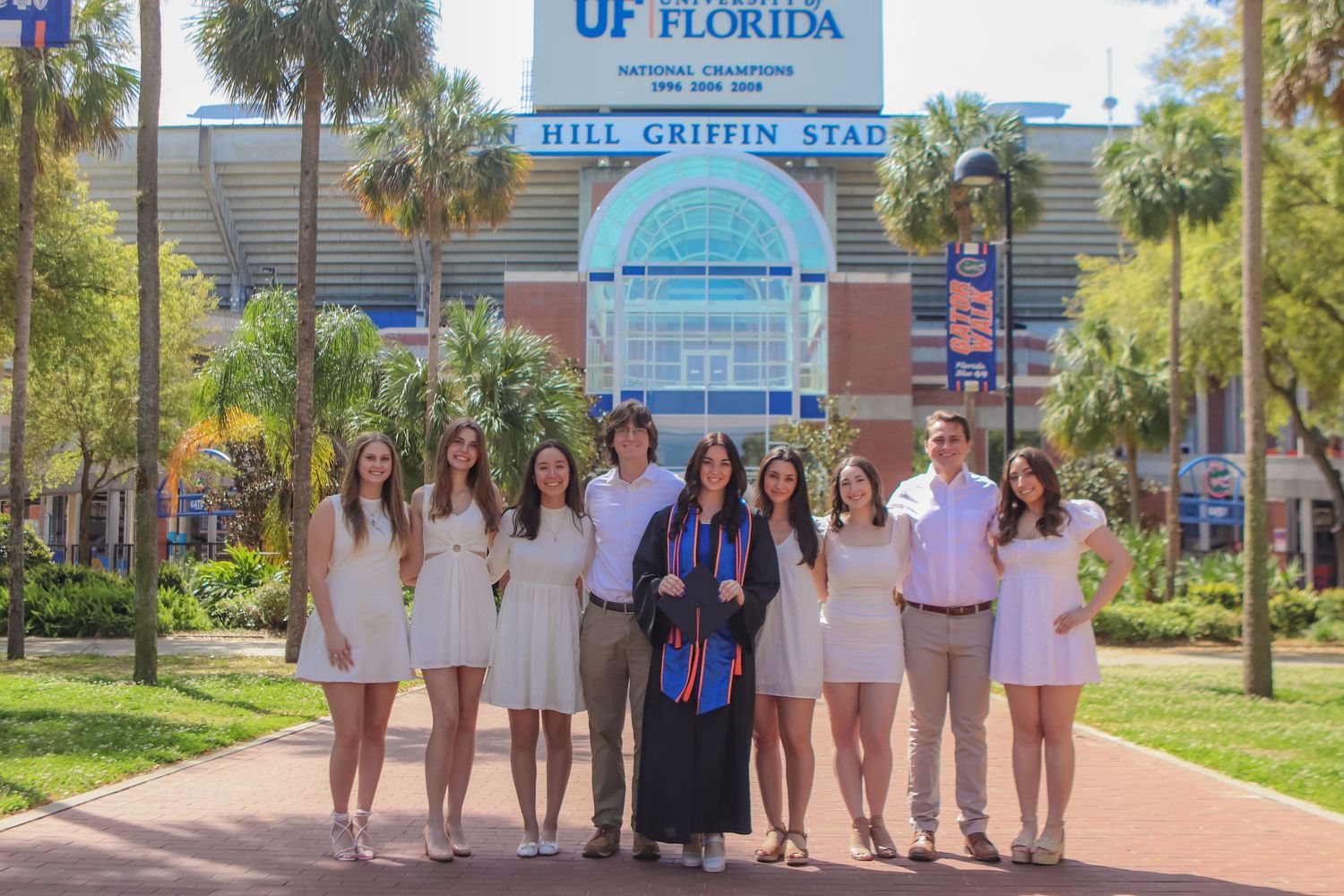 Group photo in white dresses in front of University of Florida Ben Hill Griffin Stadium entrance.