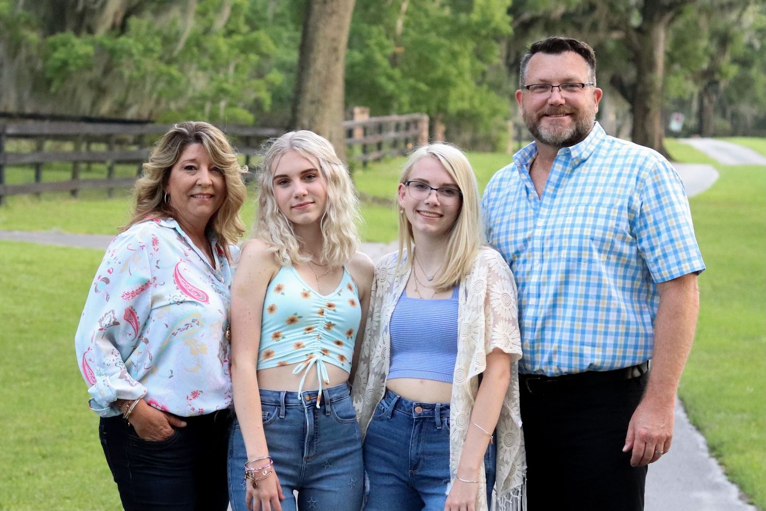 Family group poses together outdoors for graduation photos in casual attire.