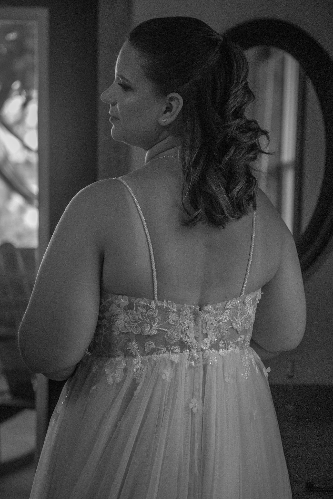 Back view of a wedding dress showing delicate lace details in black and white.